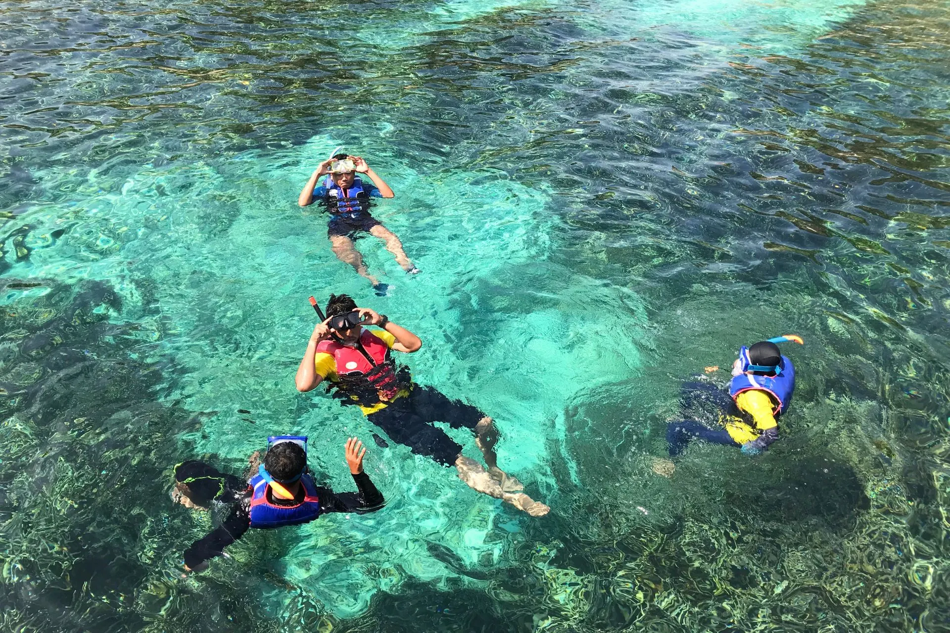 Snorkelaars drijven boven een tropisch rif in Jamaica, met kristalhelder water en zonnestralen die door het oppervlak schijnen.