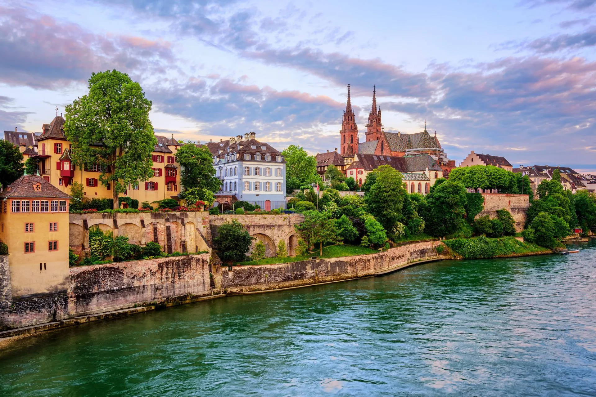 Historische stad aan de oever van de Rijn met oude stadsmuren, kerktorens en groene rivieroevers, een klassiek uitzicht langs de Rijn in Europa.
