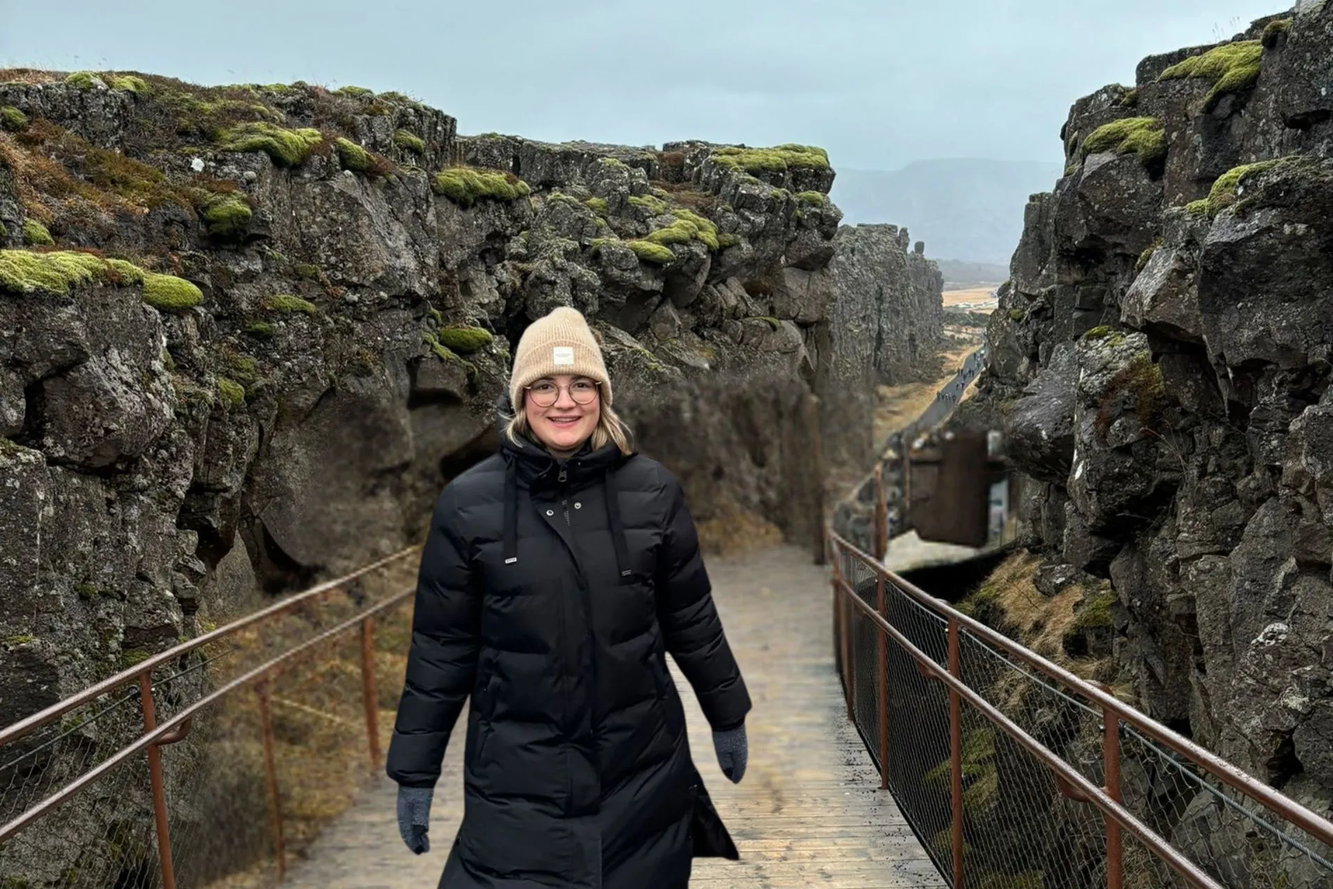 Reisadviseur Vera wandelt op een houten brug in Þingvellir National Park, omgeven door mosbegroeide rotswanden.
