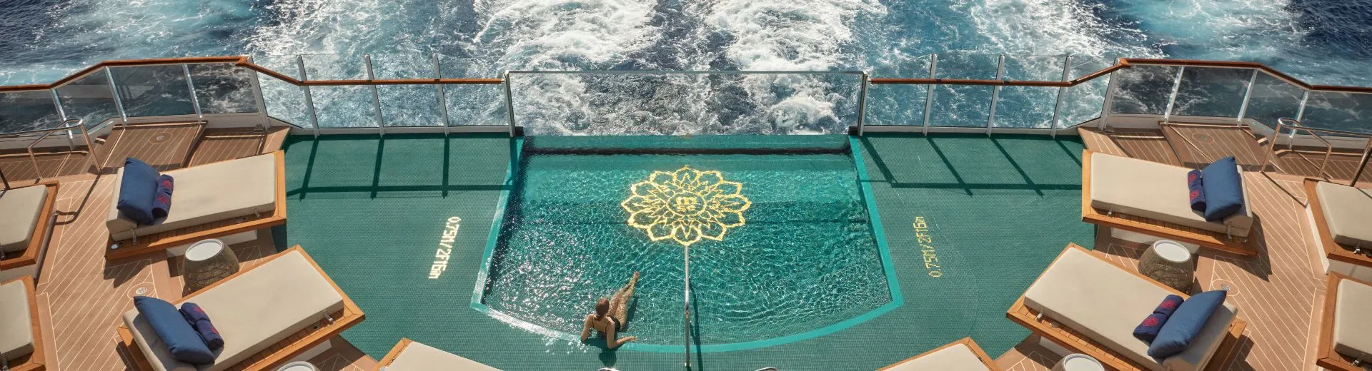 Luxe achterdek van Explora Journeys cruise met infinity pool en uitzicht op zee. Het zwembad op het achterdek van Explora I is omringd door comfortabele ligbedden met zachte kussens, ideaal voor ontspanning tijdens een ultra-luxe reis. 