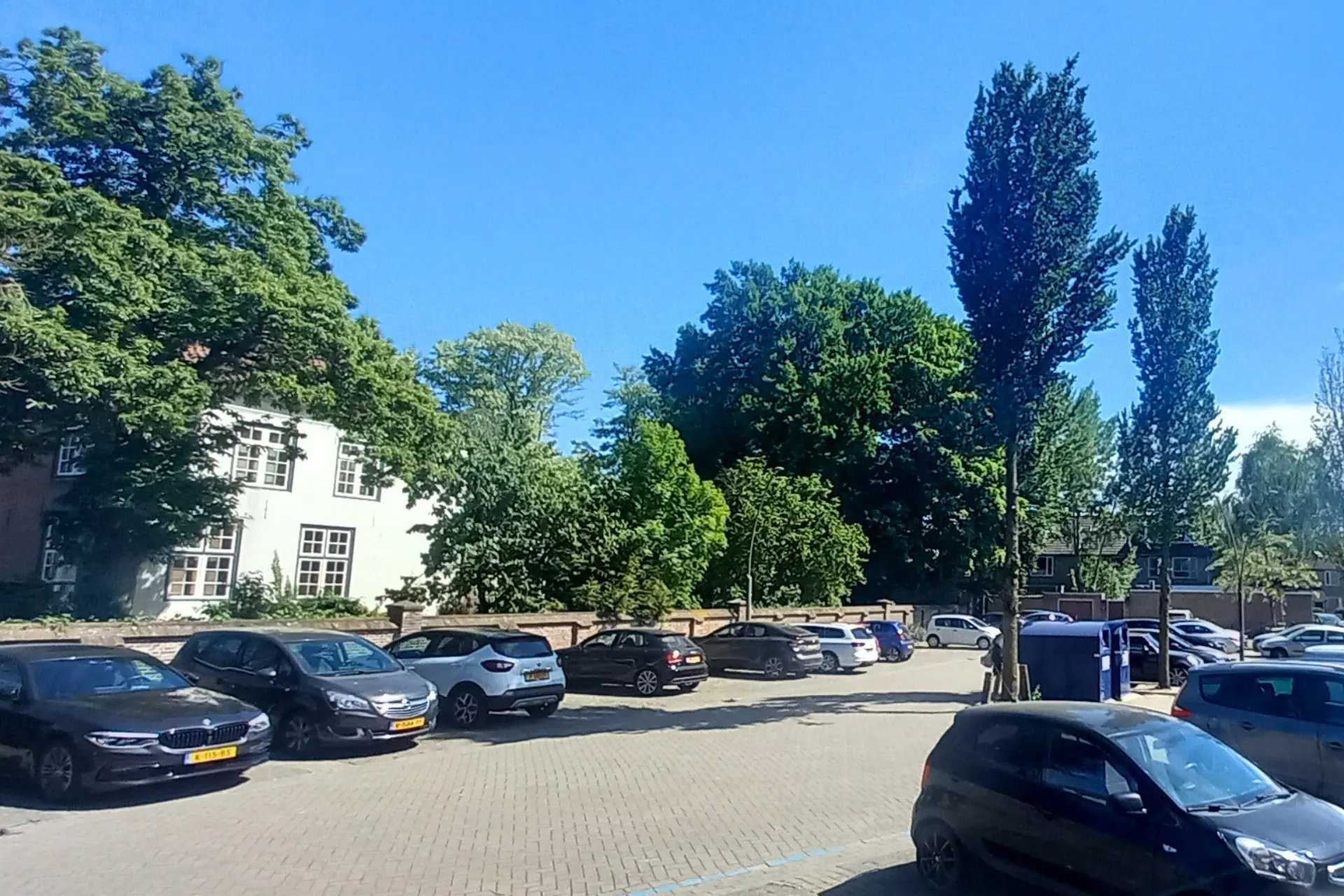 Parkeerplaats achter winkelcentrum De Driesprong in Rosmalen, met meerdere auto's.