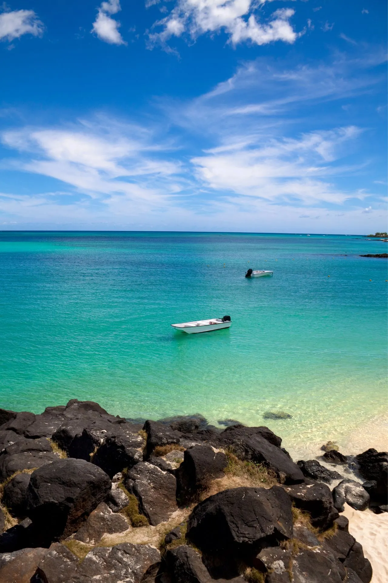 Een schilderachtig uitzicht op een helderblauwe lagune met een boot aan de kust van Mauritius. Een ideale bestemming voor wie een goedkope vakantie naar Mauritius wil boeken en genieten van ongerepte natuur.