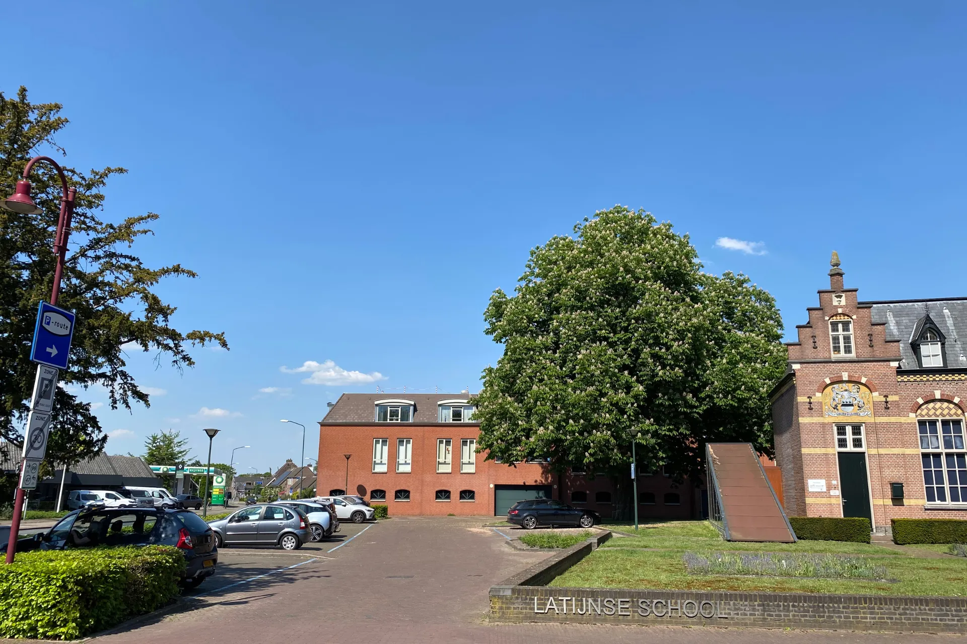 Parkeerplaats bij de Latijnse School in Gemert, met zicht op omliggende gebouwen.