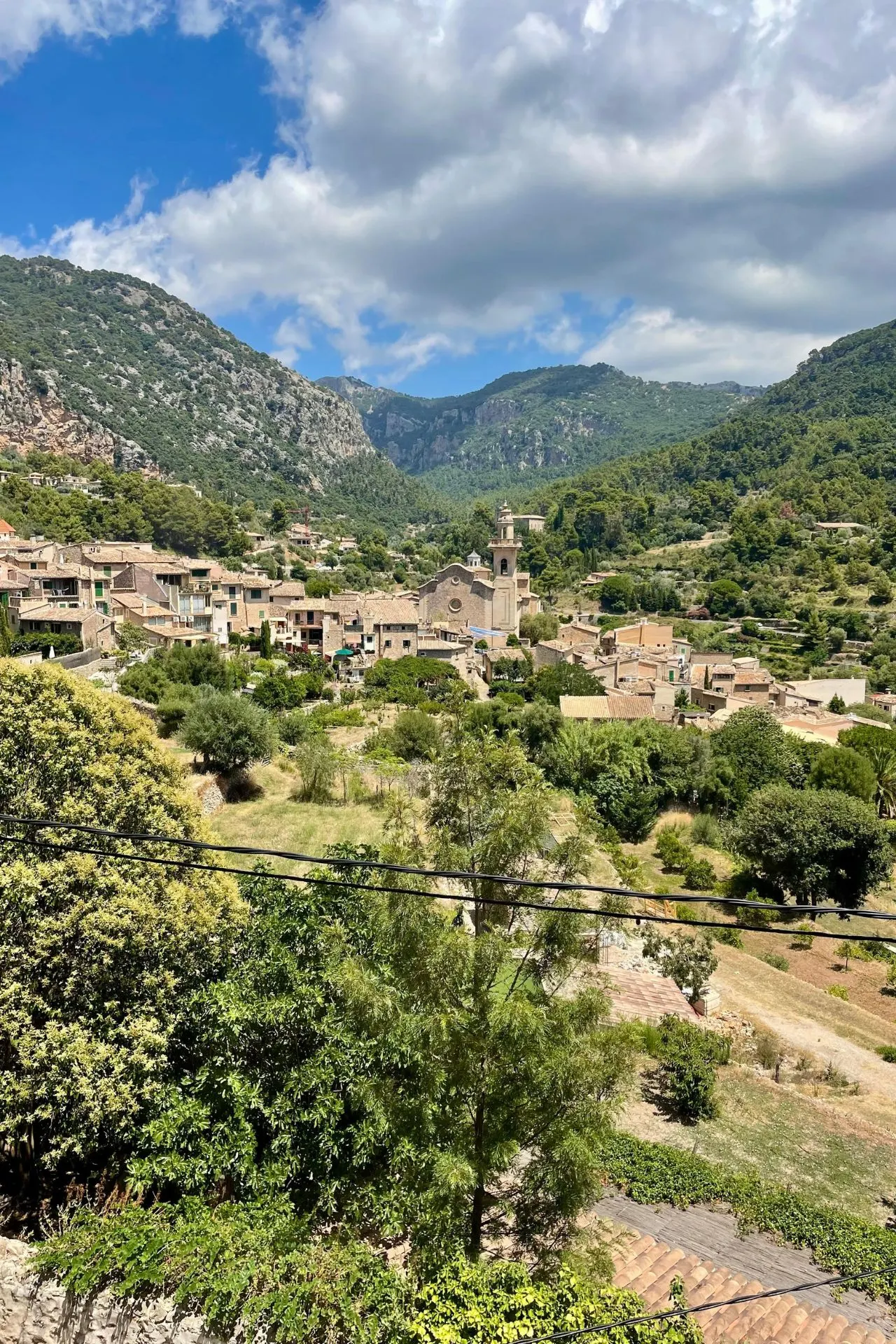 Panorama van het bergdorp Valldemossa op Mallorca, omringd door groene heuvels en bergen, met de kerk in het midden.