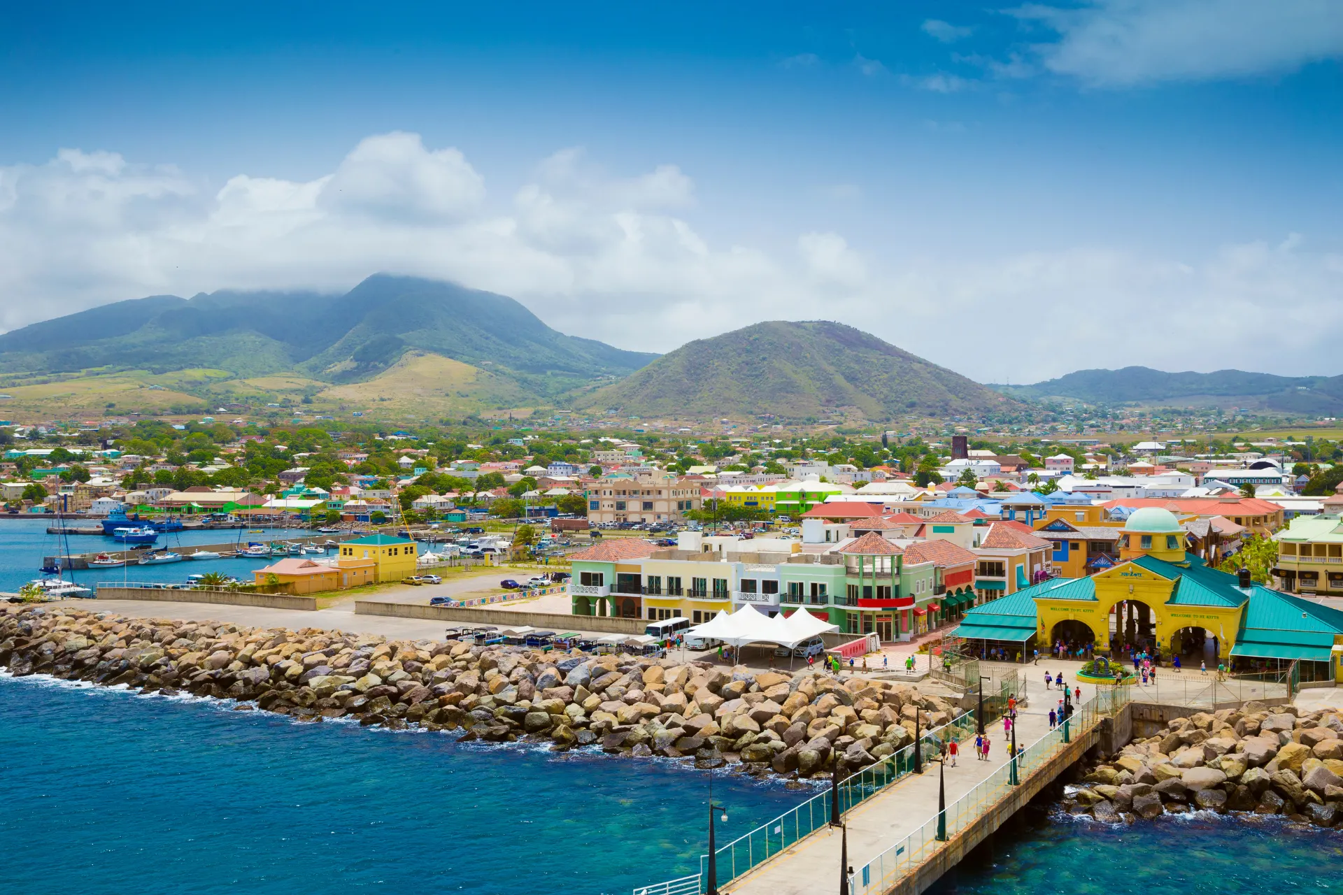 Kleurrijke haven met pier op St. Kitts, omringd door felgekleurde huisjes, met een tropische sfeer en een mix van Franse en Britse invloeden.