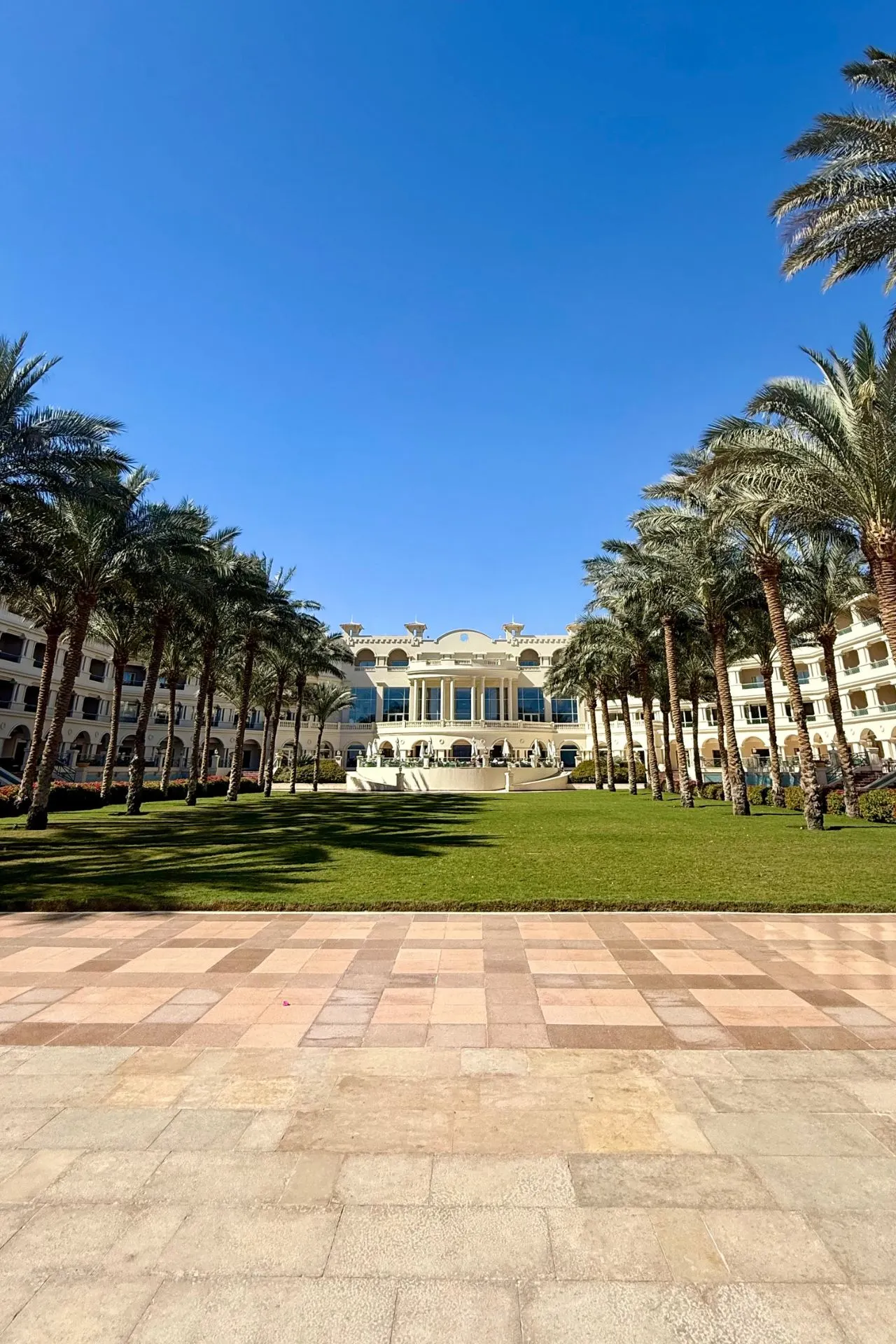 Exterieur van Baron Palace Sahl Hasheesh, een luxe resort aan de Rode Zee in Egypte met palmentuin en imposante entree.