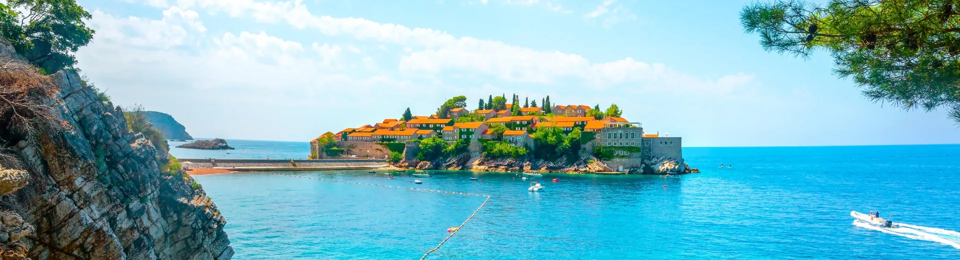 Een eiland in het midden van helderblauw water, omringd door een rustige zee en natuur.