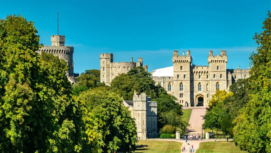 Kasteel in Engeland omringd door uitgestrekte groene velden en bomen, midden in een idyllisch landschap.
