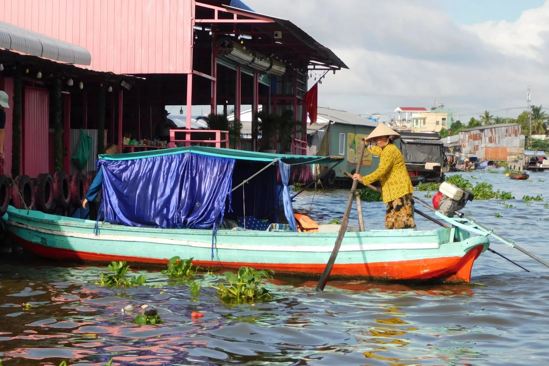 Traditionele houten boot op de Cai Rang Floating Market in de Mekong Delta, Vietnam. Lokale handelaren vervoeren dagelijks verse producten over het water, terwijl kleurrijke boten tussen de huizen en marktkramen varen. Een authentiek beeld van het dagelijkse leven in Zuid-Vietnam.
