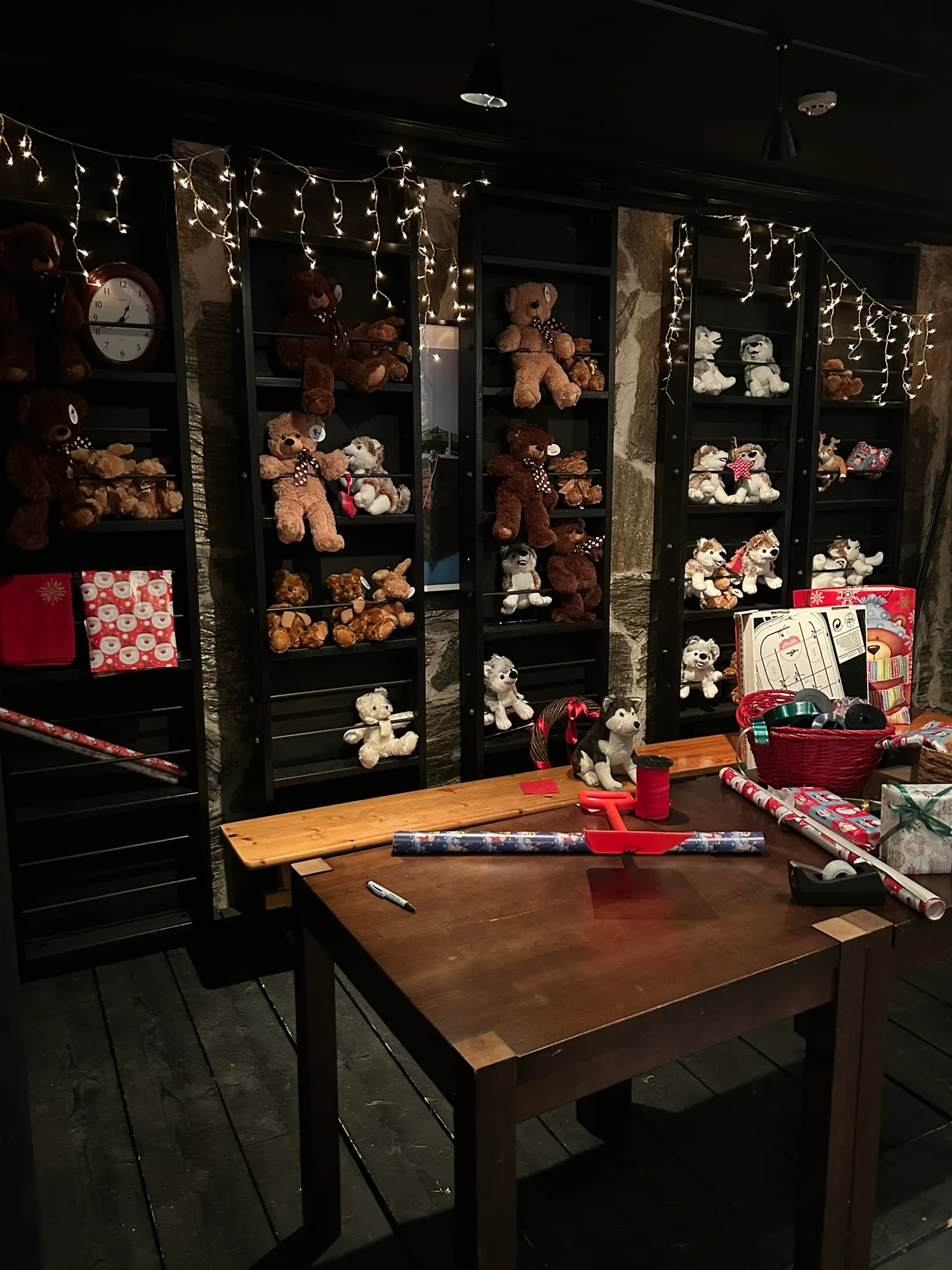 Knus ingericht huisje met teddyberen en een houten tafel met inpakpapier.