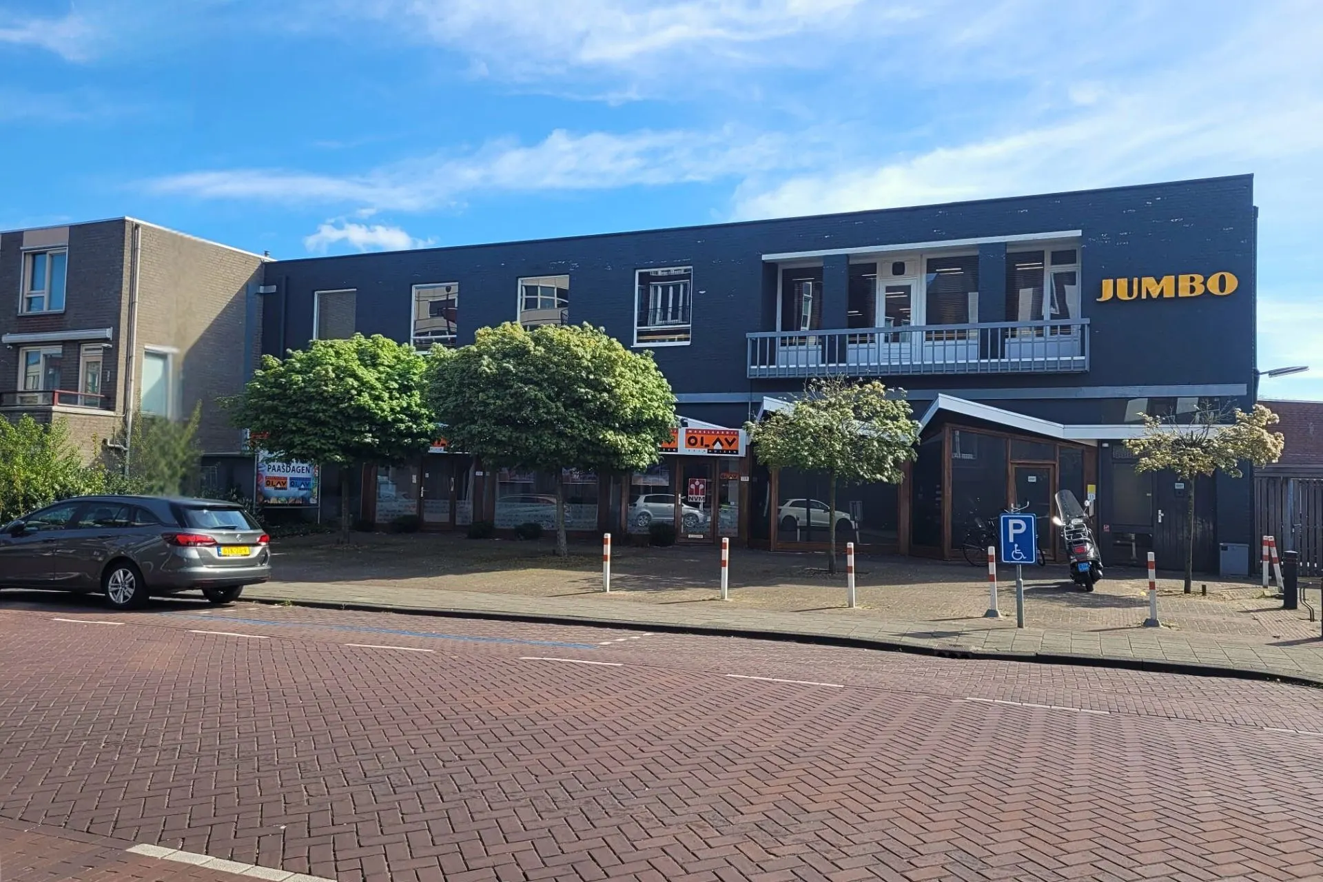  Parkeerplaats bij de Jumbo in Veghel op een zonnige dag met blauwe lucht; een rij met parkeerplaatsen waar je 2 uur mag parkeren met een blauwe schijf. Vanaf hier is het 5 minuten lopen naar Travelcenter de Wit Veghel.