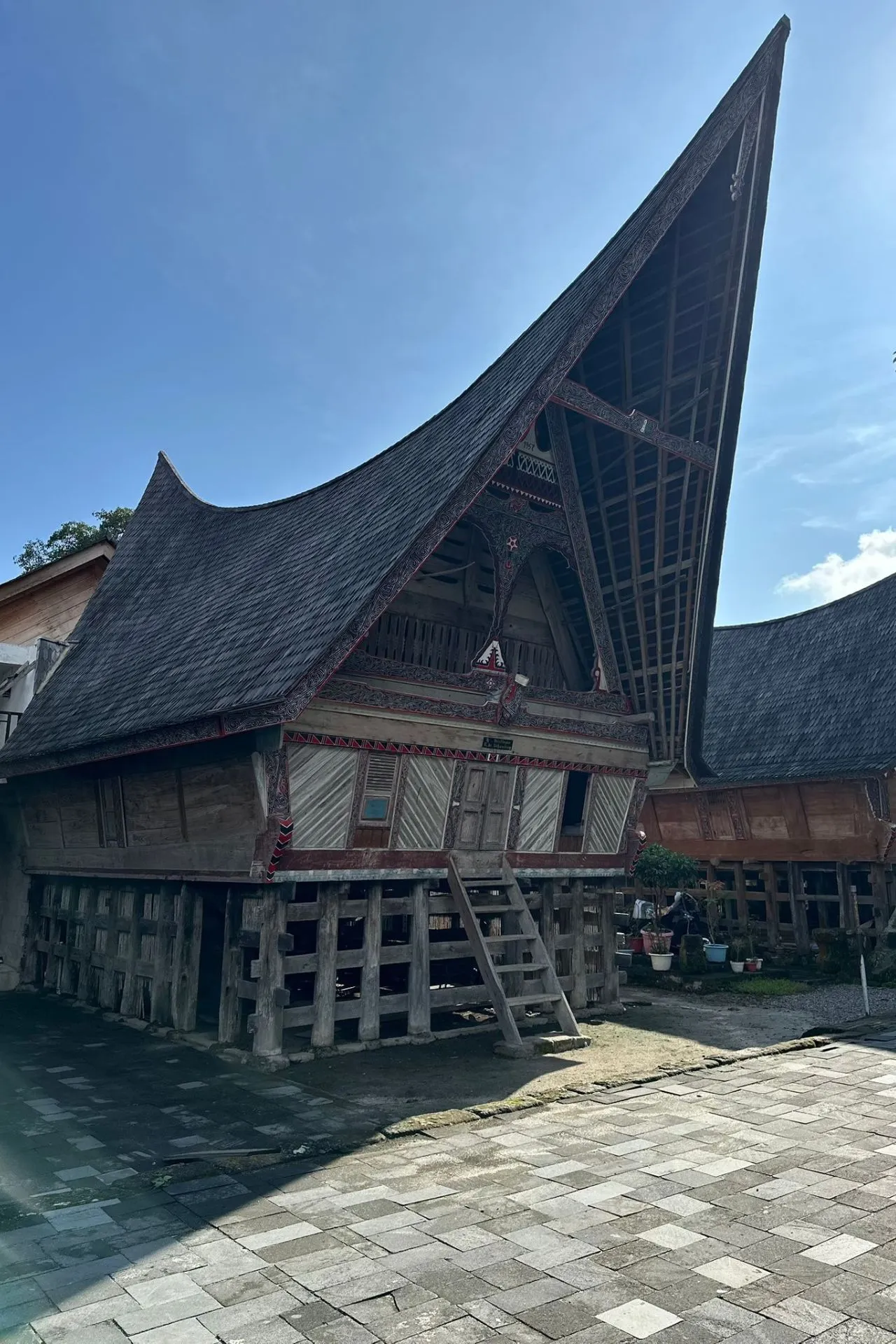 Een traditioneel huis van de Batak-stam op Sumatra met een hoog, schuin dak en gedetailleerd houtsnijwerk.