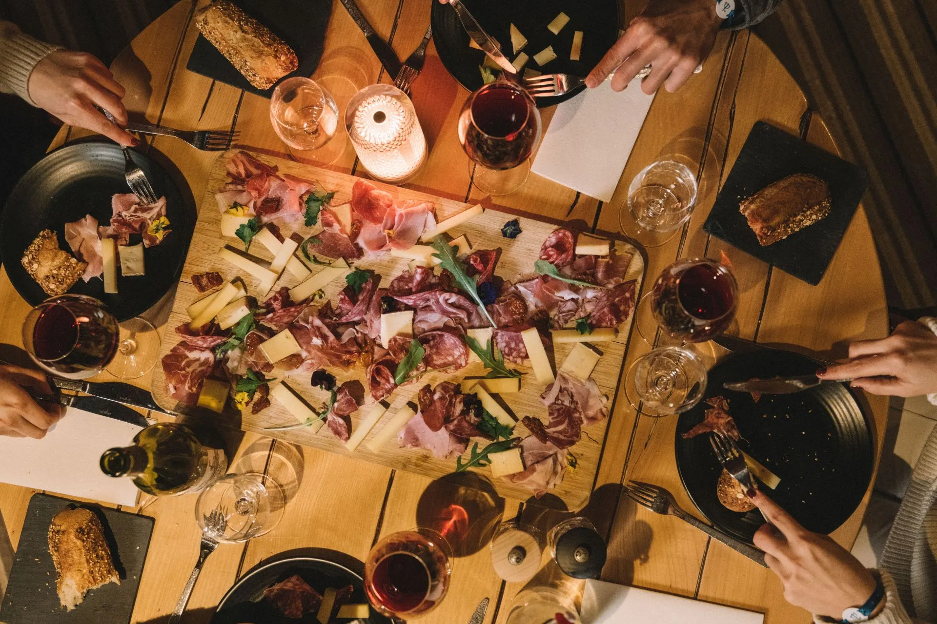 Gastronomische ervaring bij Club Med skiresort: tafel met charcuterie, kazen, brood en rode wijn in een sfeervol bergrestaurant. All-inclusive wintersportvakantie met culinaire hoogstandjes en premium dining.