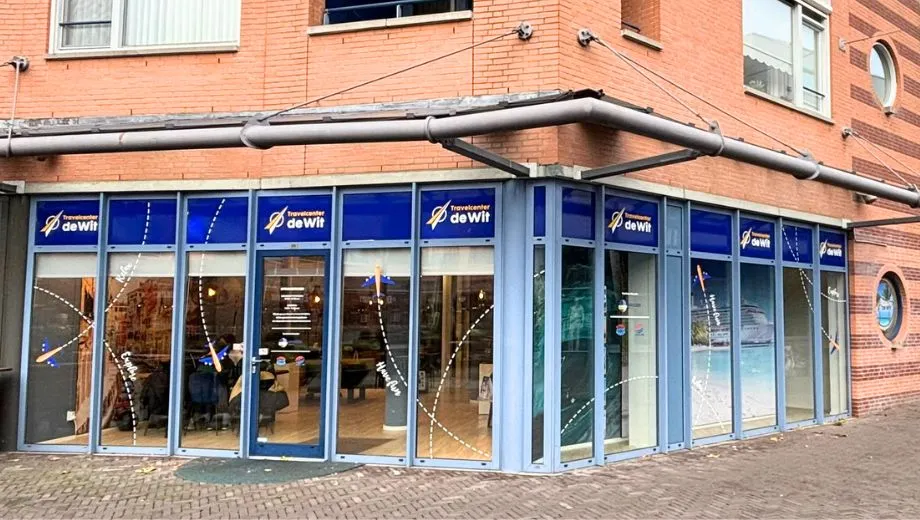 Hoek gebouw van filiaal Uden van Travelcenter de Wit. Rode stenen en blauwe kozijnen.