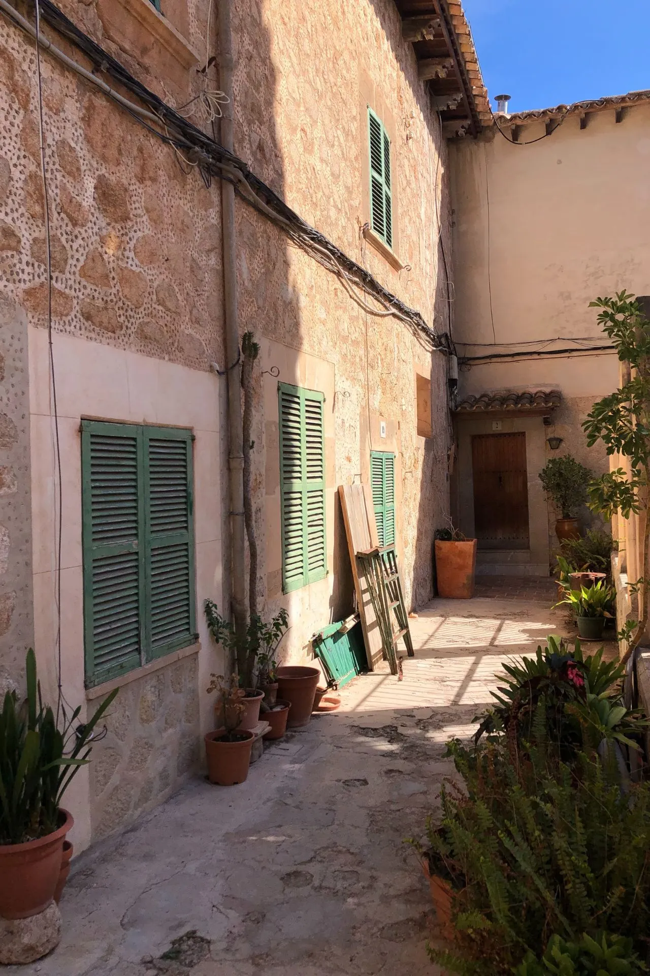 Authentieke smalle straat in Valldemossa, Mallorca, omringd door stenen huizen met groene luiken en bloempotten vol mediterrane planten. Deze idyllische plek in de Serra de Tramuntana is geliefd bij toeristen vanwege zijn rustieke charme, historische karakter en schilderachtige wandelroutes. Ideaal voor cultuur- en natuurliefhebbers tijdens een vakantie op Mallorca.
