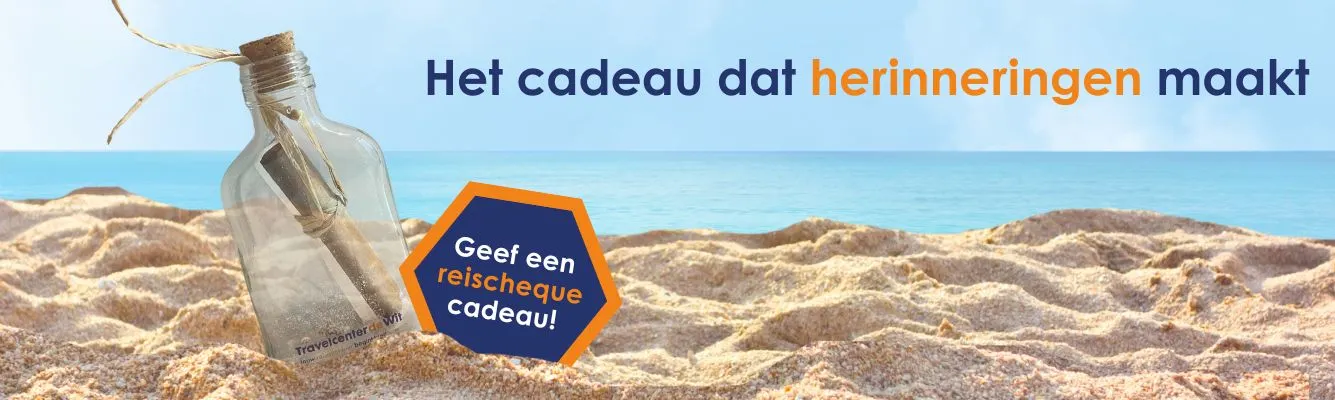 Reischeque van Travelcenter de Wit in een glazen fles op een zonnig zandstrand, met op de achtergrond de zee en een heldere blauwe lucht. De afbeelding symboliseert het geven van een vakantie cadeau en is geschikt voor een pagina over een reischeque, cadeaubon voor een reis of origineel reiscadeau.