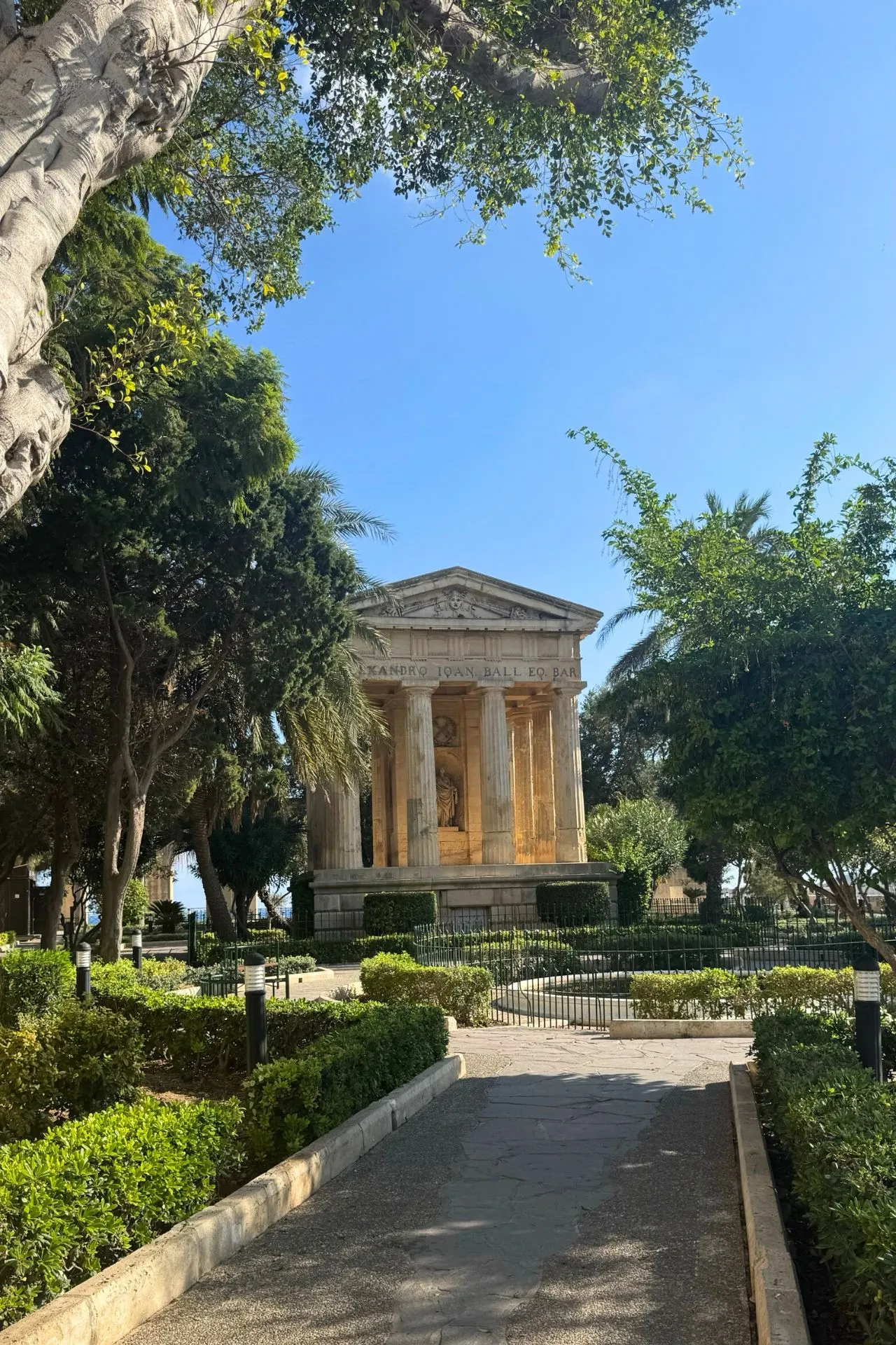 Parkje in Valletta, Malta, met een oude tempel omringd door groene natuur.