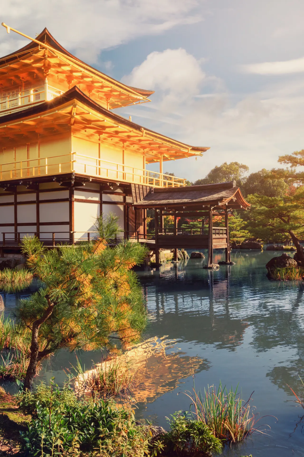 Kinkaku-ji, het iconische Gouden Paviljoen van Kyoto, weerspiegeld in het serene water van de vijver, omgeven door een prachtig aangelegde tuin die het adembenemende uitzicht compleet maakt.
