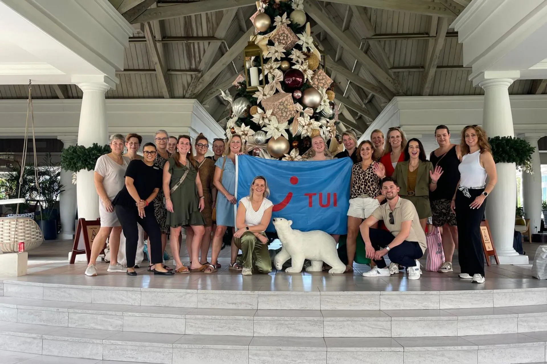 Groepsfoto bij een prachtig versierde kerstboom in een resort op Curaçao, met TUI-banner en feestelijke decoraties. Deze setting benadrukt de combinatie van tropische vakantie en kerstviering. Perfect voor reisorganisaties, influencers en vakantiegangers die Curaçao promoten als winterzonbestemming.
