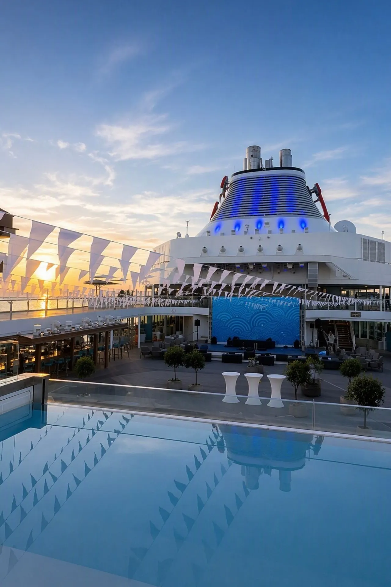 Het buitendek van de Mein Schiff Flow is klaar voor een avond vol entertainment terwijl de zon ondergaat boven zee. Met een podium, sfeervolle verlichting en ruime zit- en ontmoetingsplekken vormt dit dek het decor voor diverse thema-avonden en live-optredens tijdens de cruise. De combinatie van zeezicht en entertainment maakt deze locatie extra bijzonder.