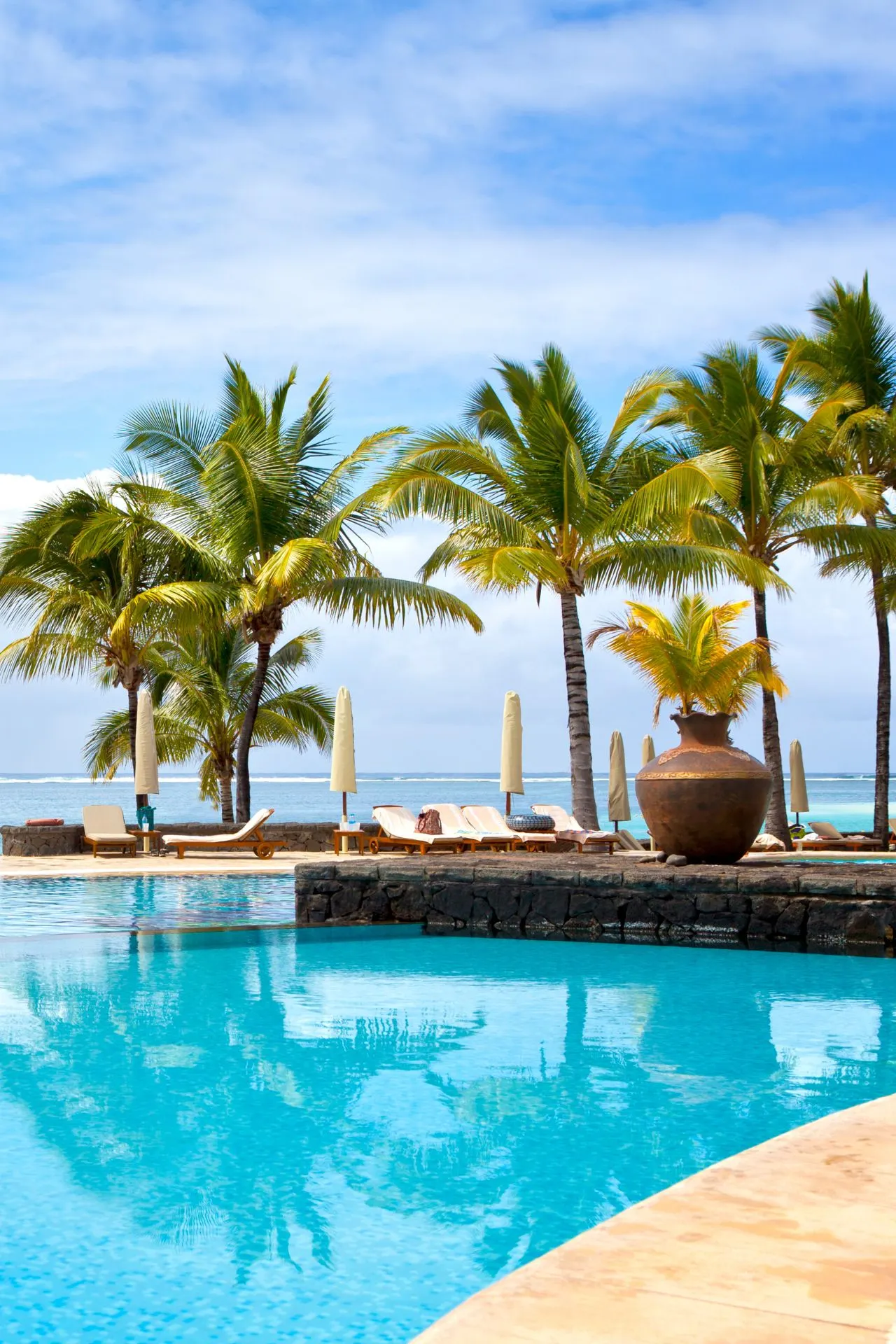 Een luxe resort met een zwembad en palmbomen aan de kust van Mauritius. Een ideale bestemming voor wie een all-inclusive vakantie naar Mauritius wil boeken.