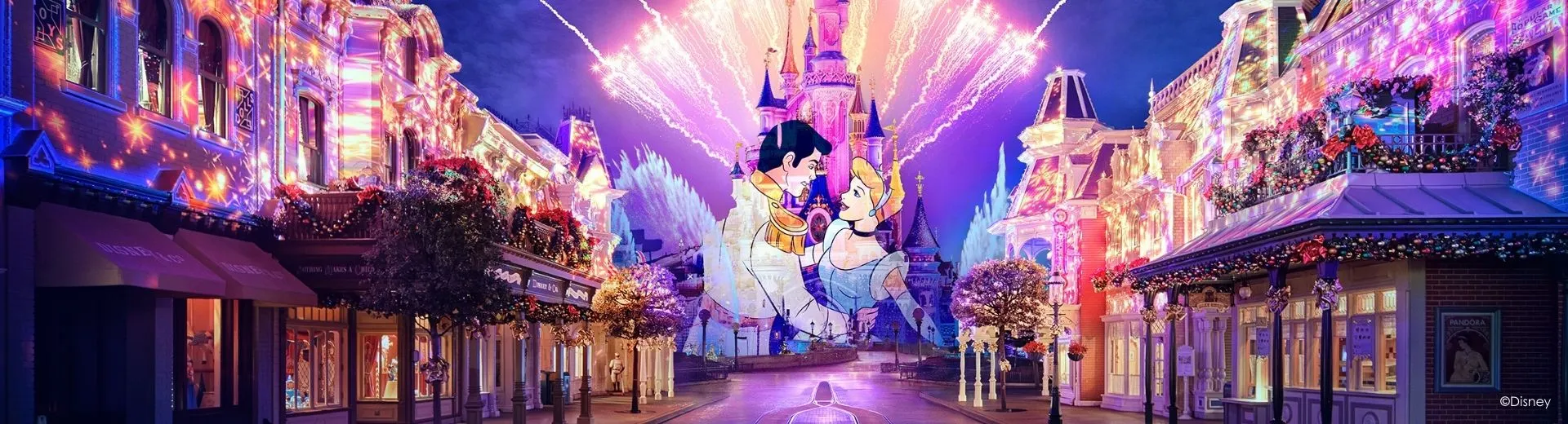 Een betoverende avond in Disneyland Parijs met kleurrijke lichtprojecties op de gebouwen van Main Street, een spectaculair vuurwerk boven het iconische kasteel en een romantische projectie van Assepoester en haar prins op de gevel. De straat is versierd met kerstdecoraties en bloemen, wat een magische en feestelijke sfeer creëert.