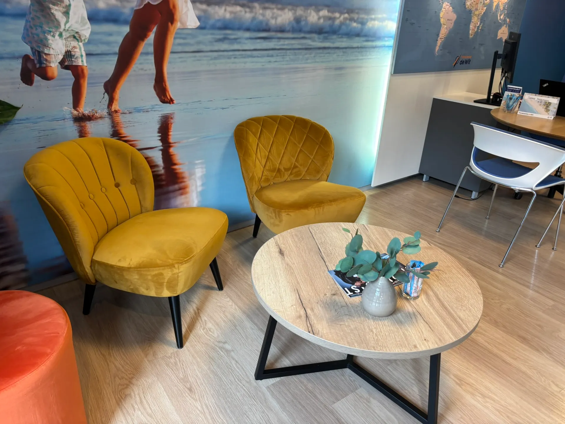Gezellig zithoekje met twee gele velvet stoelen en een ronde salontafel op een lichte vloer.