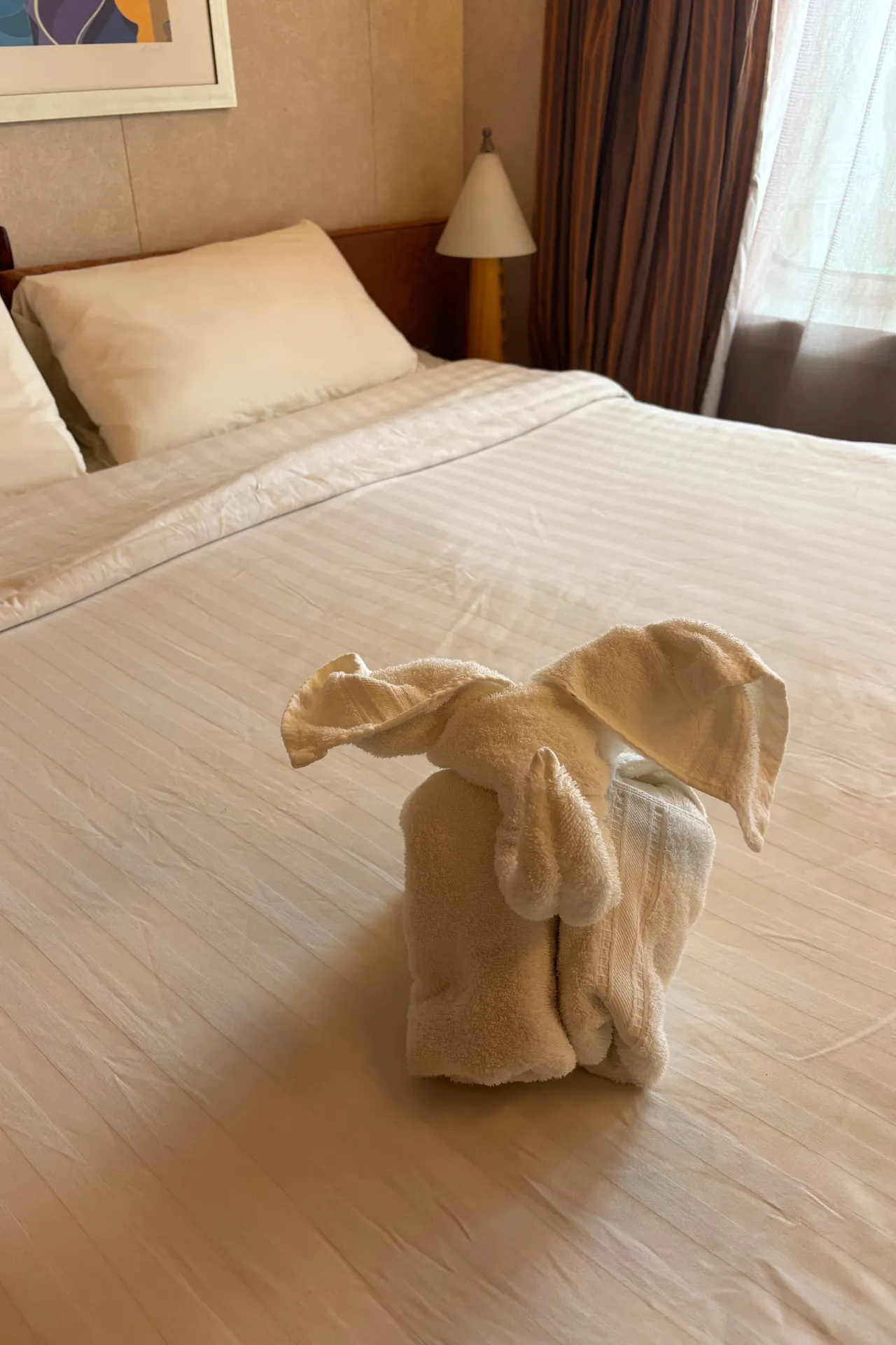 Creatief gevouwen handdoek in de vorm van een dier, een speels detail op het bed in de kamer van de Costa Diadema.