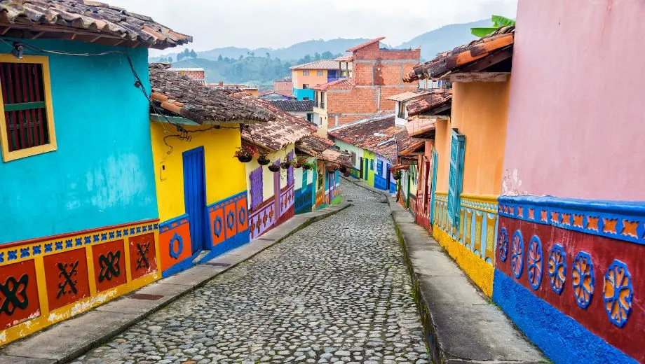 Gekleurde straat in een traditioneel Colombiaans dorp met kleurrijke huizen, sfeervolle gevels en een karakteristieke kinderkopjesweg. De levendige architectuur en authentieke sfeer weerspiegelen de rijke cultuur van Colombia, een populaire bestemming voor een afwisselende rondreis door Zuid-Amerika.
