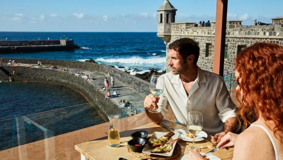 Terras aan zee met uitzicht op een natuurlijke badzone, golven en historische stenen muren in Puerto de la Cruz op Tenerife.