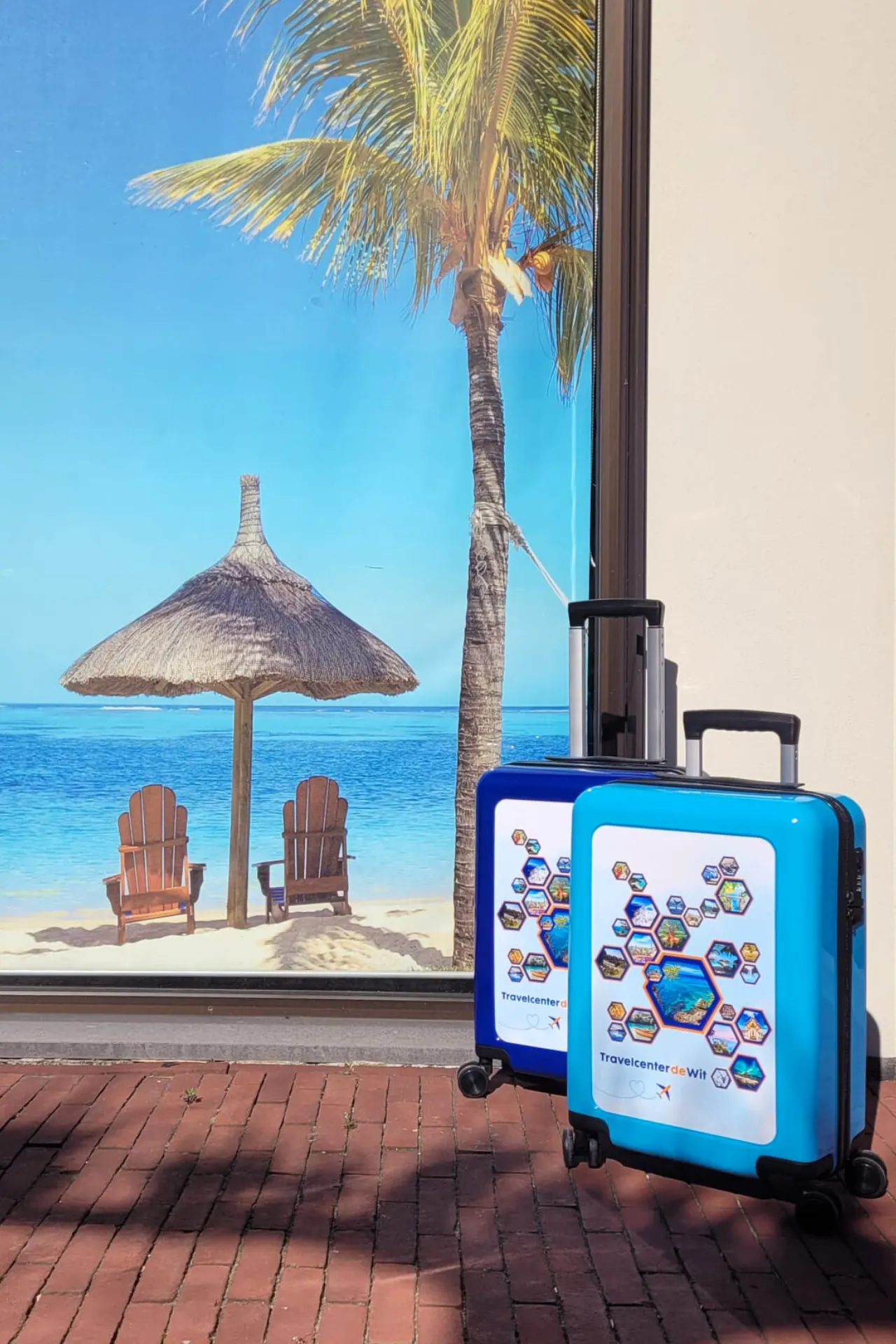 Zijkijk van twee blauwe handbagage trolleys van Travelcenter de Wit, stralend onder de zon. De koffers hebben een stevig, modern ontwerp en zijn uitgerust met vier wielen voor ultiem gemak tijdens reizen. De zonnige sfeer benadrukt de ideale keuze voor vakantiegangers op zoek naar een praktische en stijlvolle reistas.