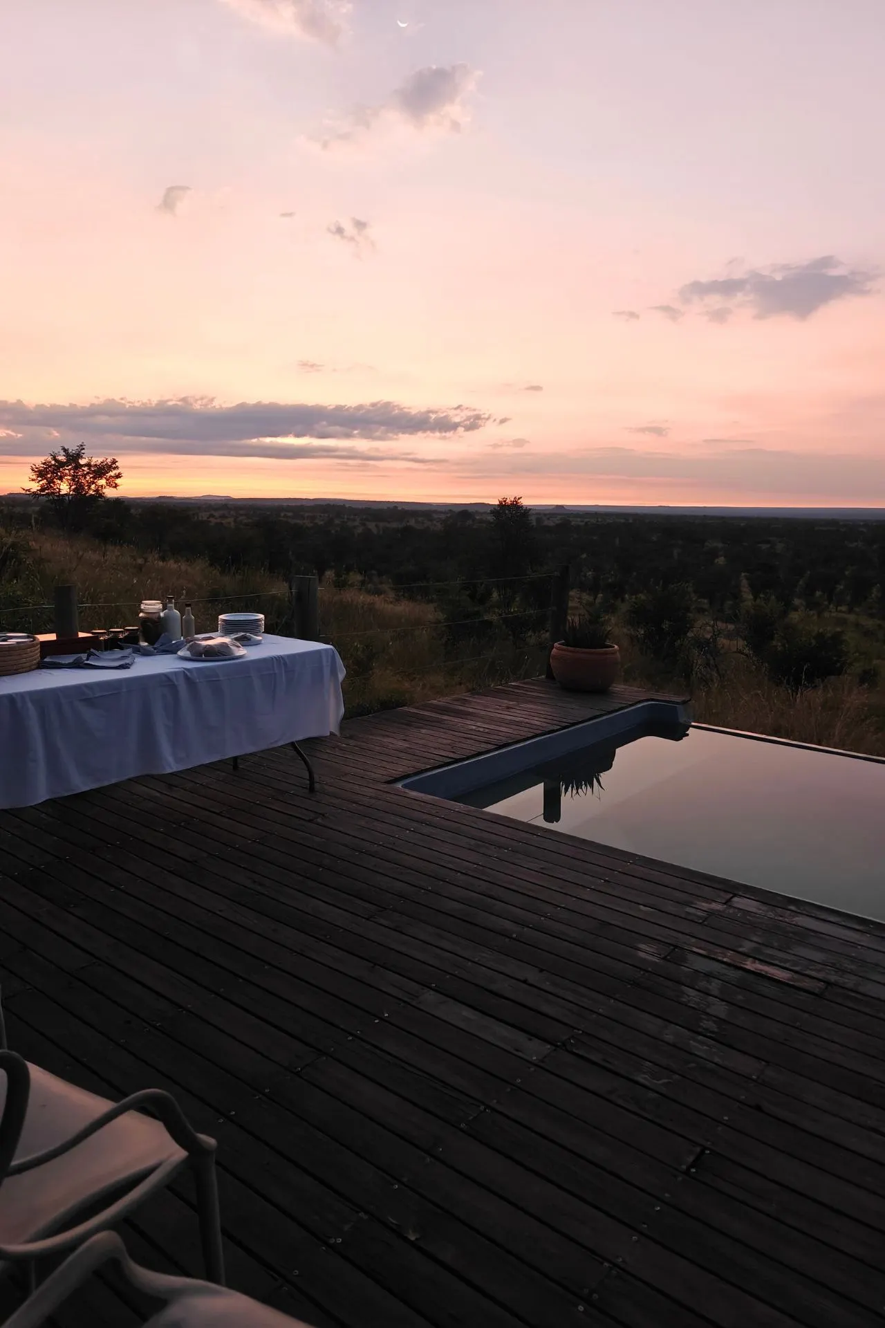 Gedekte tafel bij het zwembad met zonsopkomst en adembenemende roze lucht