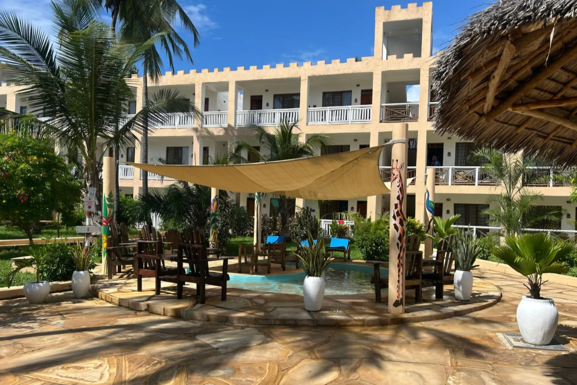 Reef & Beach Resort in Jambiani op Zanzibar, omringd door tropische tuinen met palmbomen en een sfeervol terras aan het zwembad. Dit populaire all-inclusive resort combineert een authentieke Afrikaanse sfeer met comfortabele kamers, relaxte faciliteiten en een rustige ligging aan de kust van Zanzibar in Tanzania.