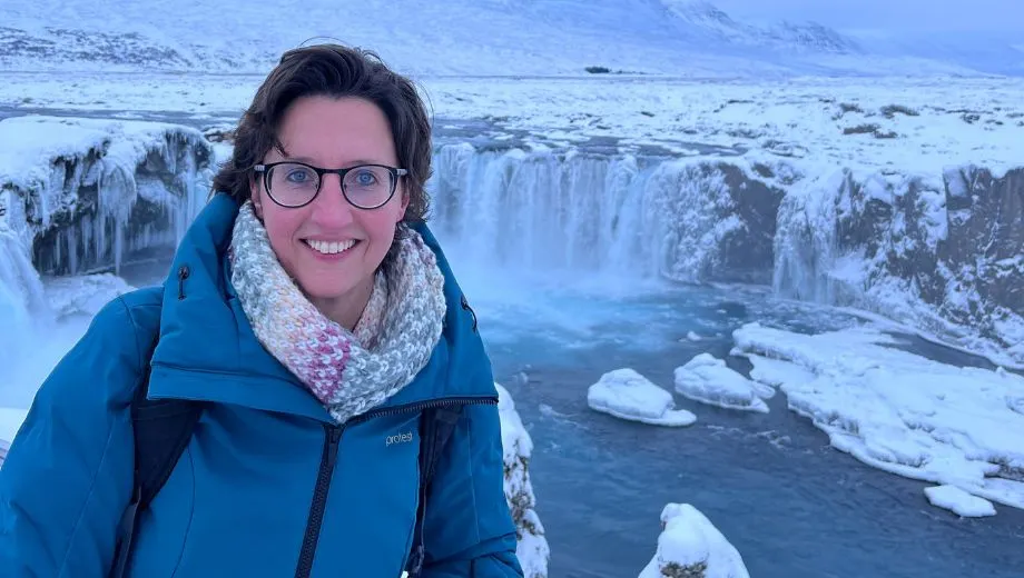 Reisspecialist Susan Wolfs bij de besneeuwde Godafoss‑waterval in Noord‑IJsland tijdens de winter.