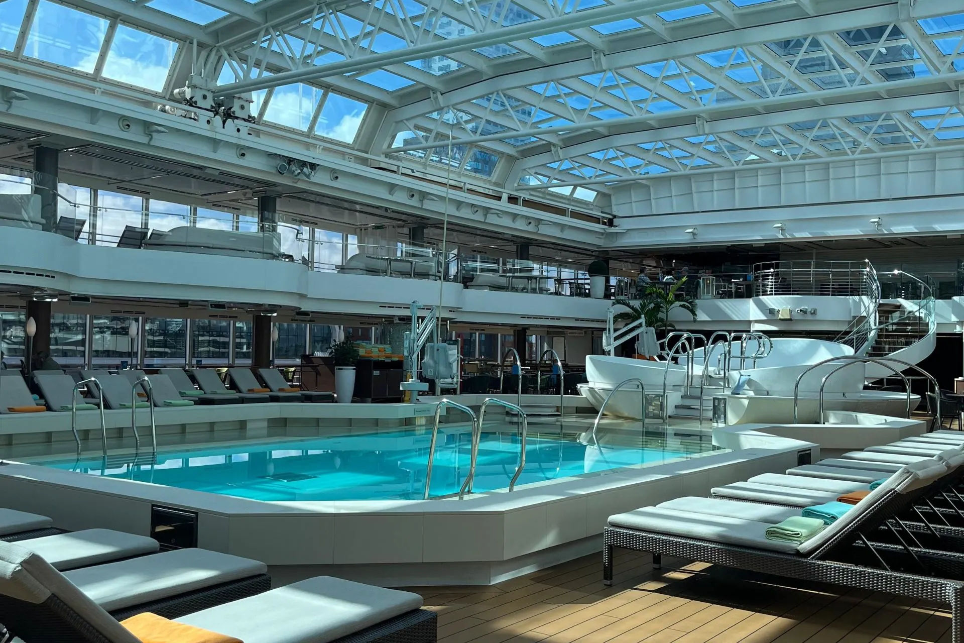 Het overdekte zwembad op de Nieuw Statendam van Holland America Line, omringd door luxe ligstoelen, met een glazen plafond dat zonlicht binnenlaat.