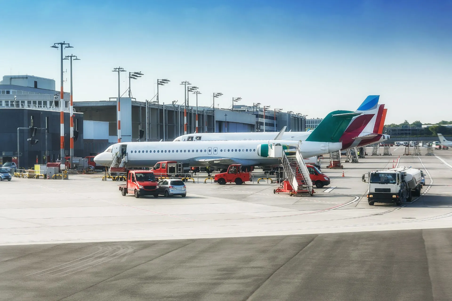 Drukke activiteiten op het vliegveld met vliegtuigen aan de gate en servicevoertuigen op de landingsbaan. Vluchten vanaf Dortmund Airport vertrekken dagelijks naar verschillende bestemmingen. Het vertrek vanaf luchthaven Dortmund biedt reizigers een breed scala aan mogelijkheden voor een soepele reis.