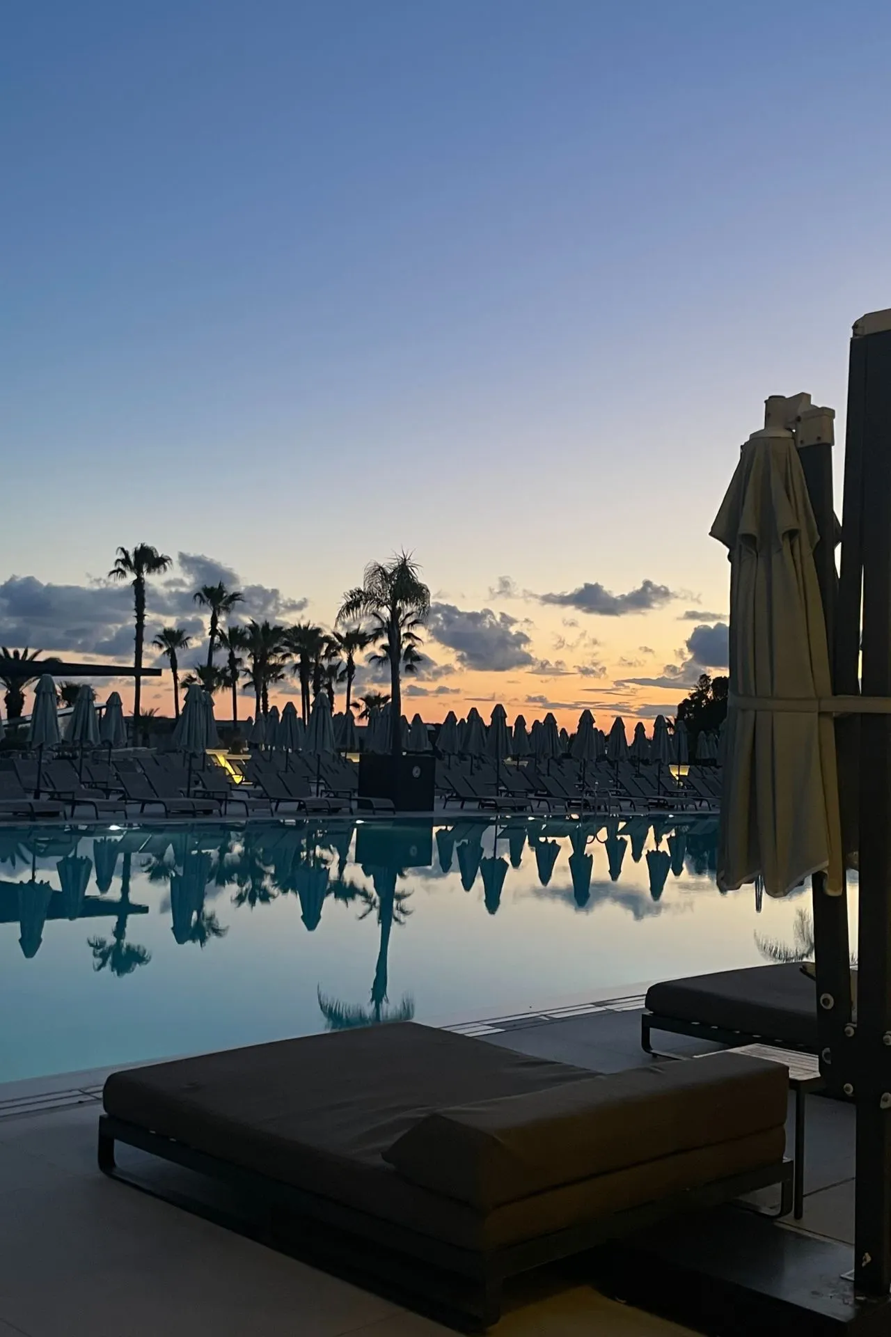 Zonsondergang bij het zwembad van een hotel in Antalya, met warme kleuren die de rustige sfeer van de avond versterken