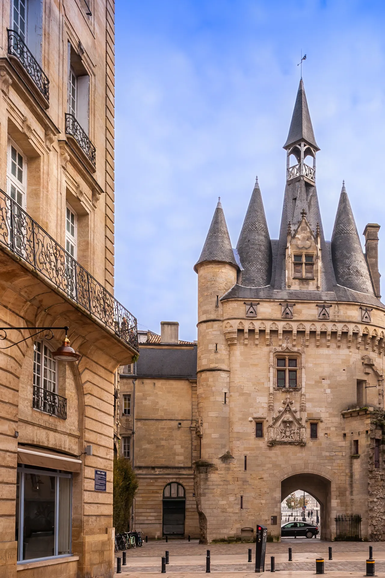Historisch stadsbeeld in Aquitaine met een indrukwekkende middeleeuwse poort en torens die elegant oprijzen tegen een heldere blauwe lucht. De zandkleurige gevels van de gebouwen stralen authenticiteit en charme uit, terwijl de gedetailleerde architectuur een rijk cultureel erfgoed weerspiegelt. Deze pittoreske locatie is ideaal voor liefhebbers van geschiedenis, architectuur en Franse cultuur, en nodigt uit tot ontspannen wandelingen door sfeervolle straatjes vol karakter en historische bezienswaardigheden.