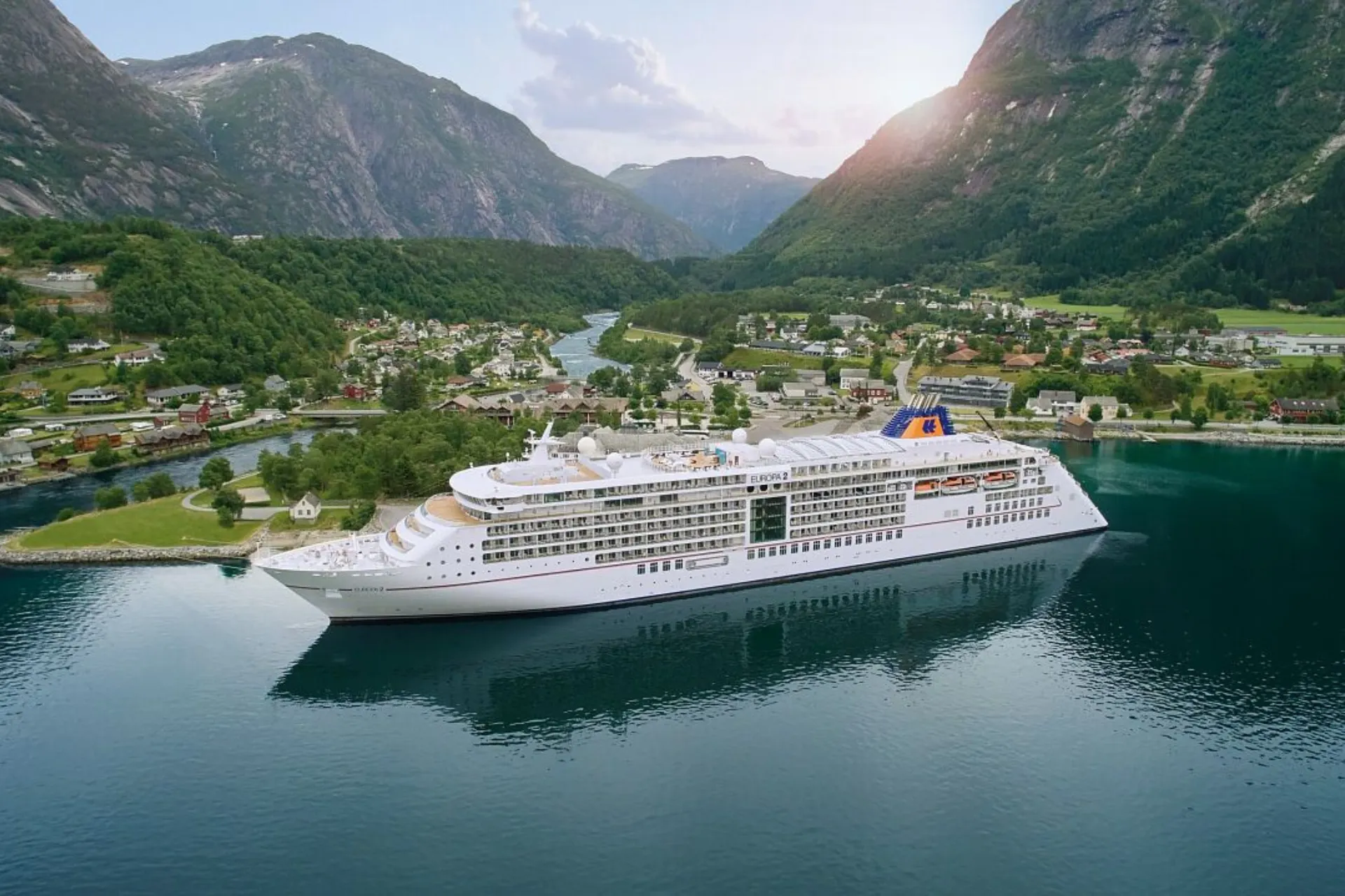  Schip van Hapag Lloyd Cruises in Noorwegen, omringd door groene heuvels en indrukwekkende bergen op de achtergrond.