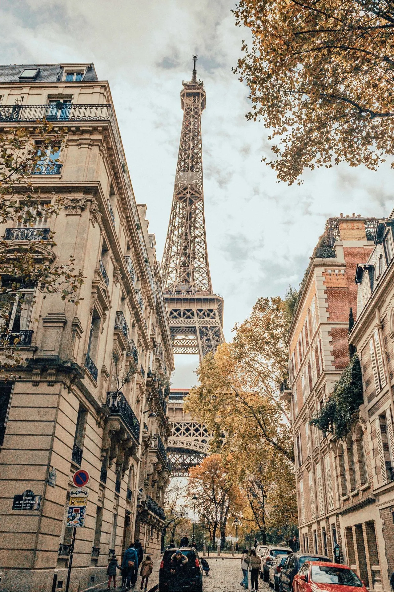 Mooie foto genomen door een smalle straat in Parijs Frankrijk, je ziet in de verte de Eiffel toren en aan de zijkant gebouwen en bomen.