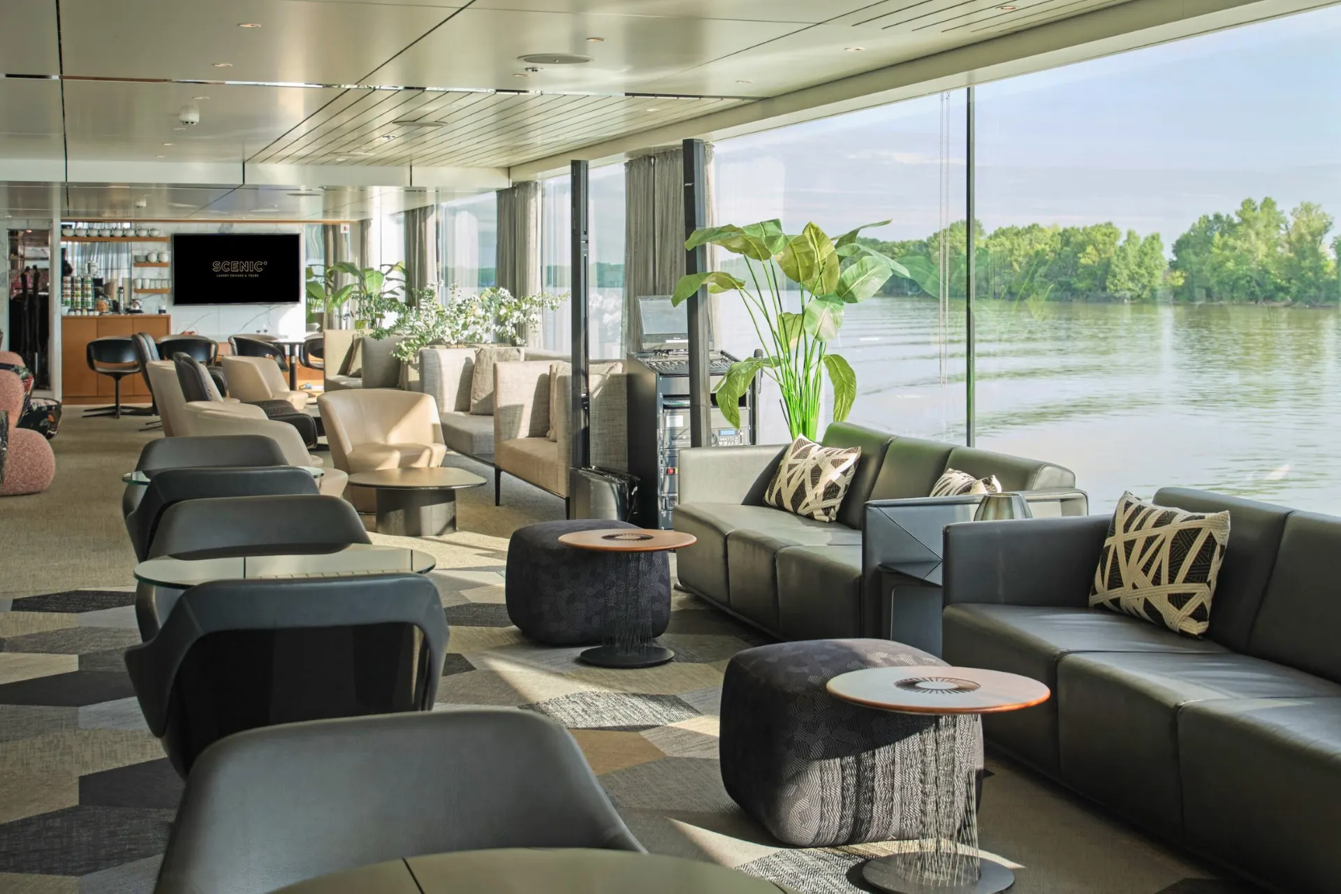 Ruime publieke lounge aan boord van Scenic schip met grote raampartijen en uitzicht op het water