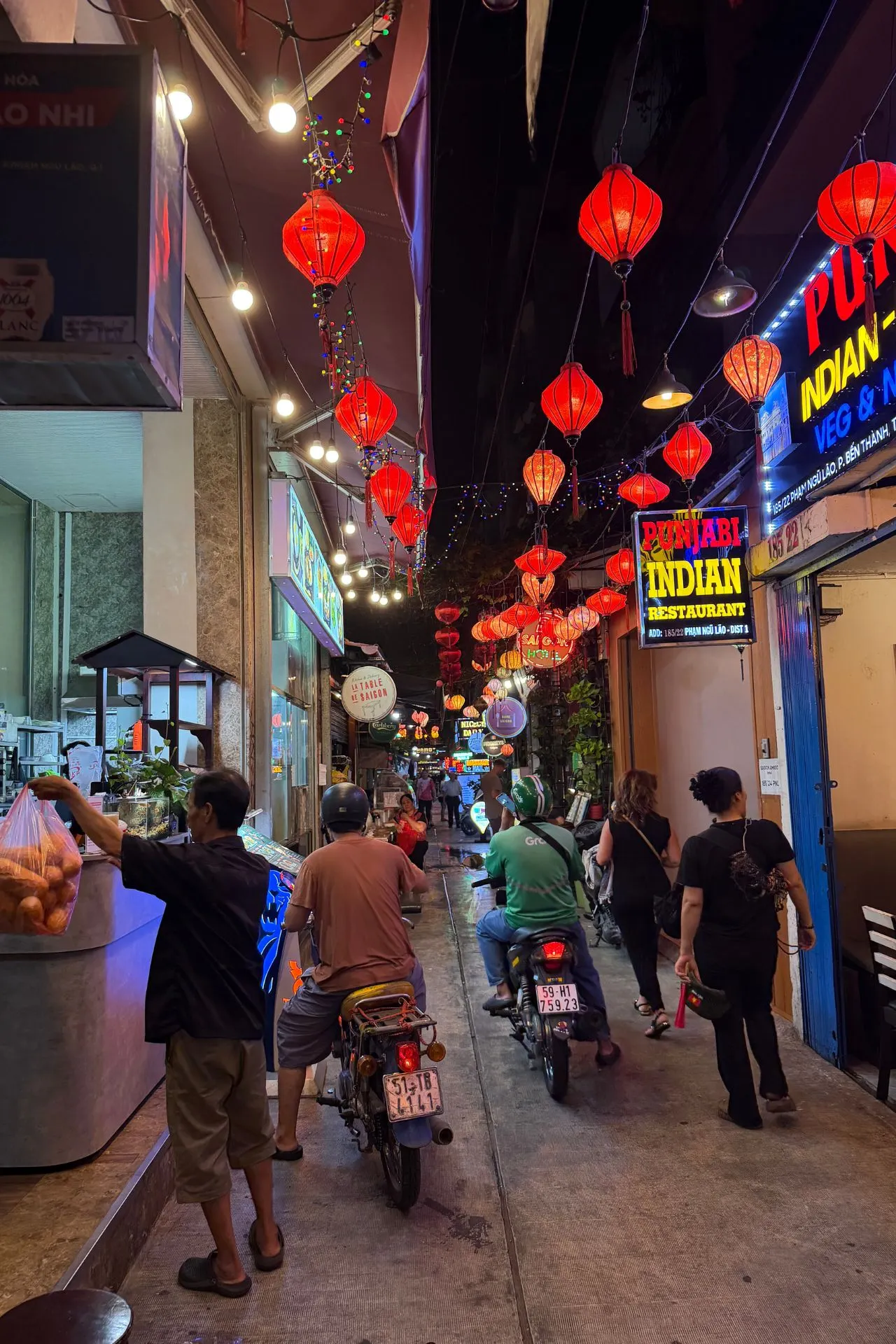 Sfeervol straatje in Ho Chi Minhstad, Vietnam, verlicht door tientallen rode lampionnen. Tussen restaurants, winkels en locals op scooters ervaar je het bruisende stadsleven. Een kleurrijke en levendige plek die perfect de energie van deze metropool weerspiegelt.
