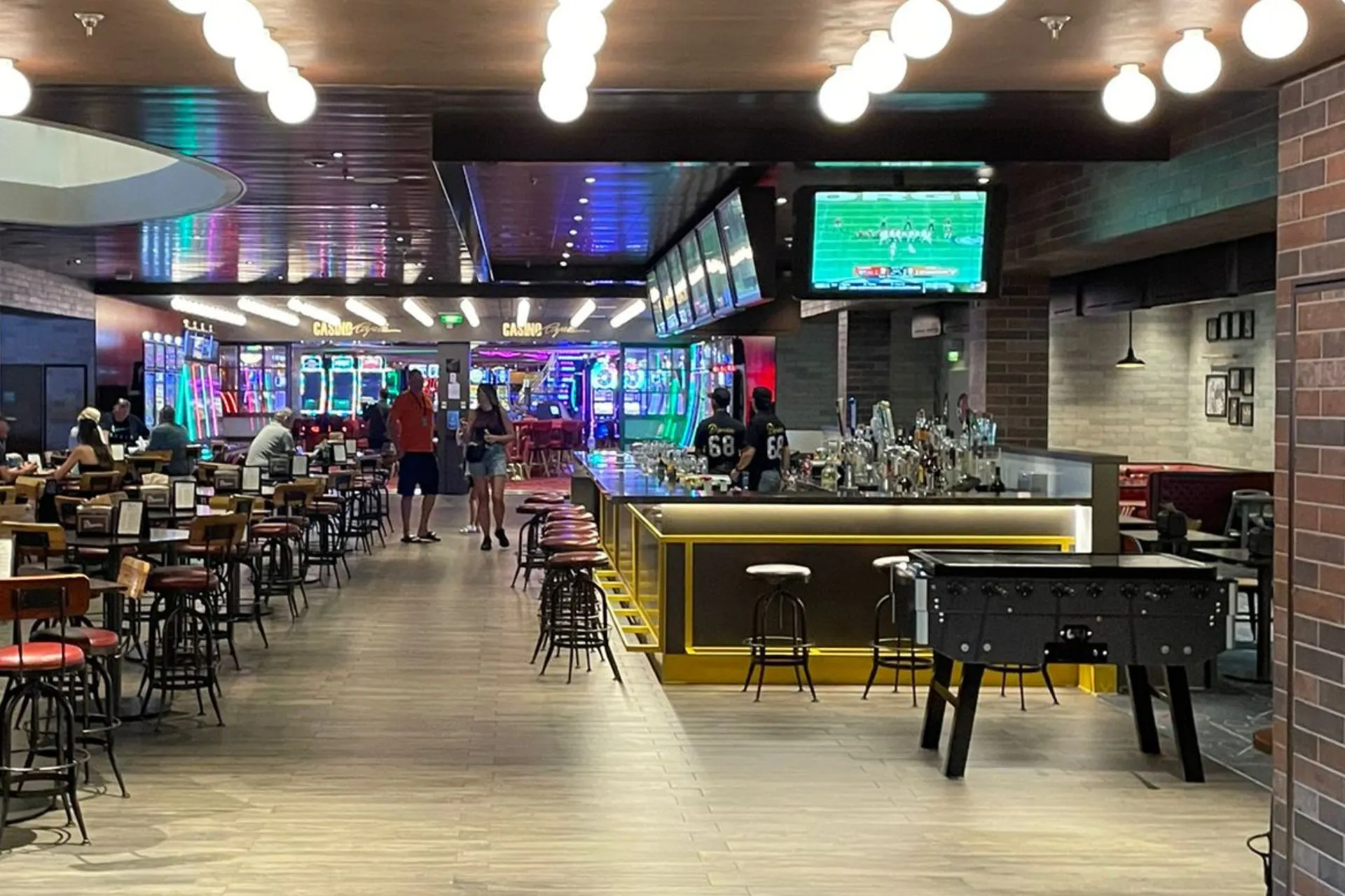 Speelse bar en arcade op de Independence of the Seas, met lange bar, tafels, flipperkasten en verlichte speelautomaten op de achtergrond.