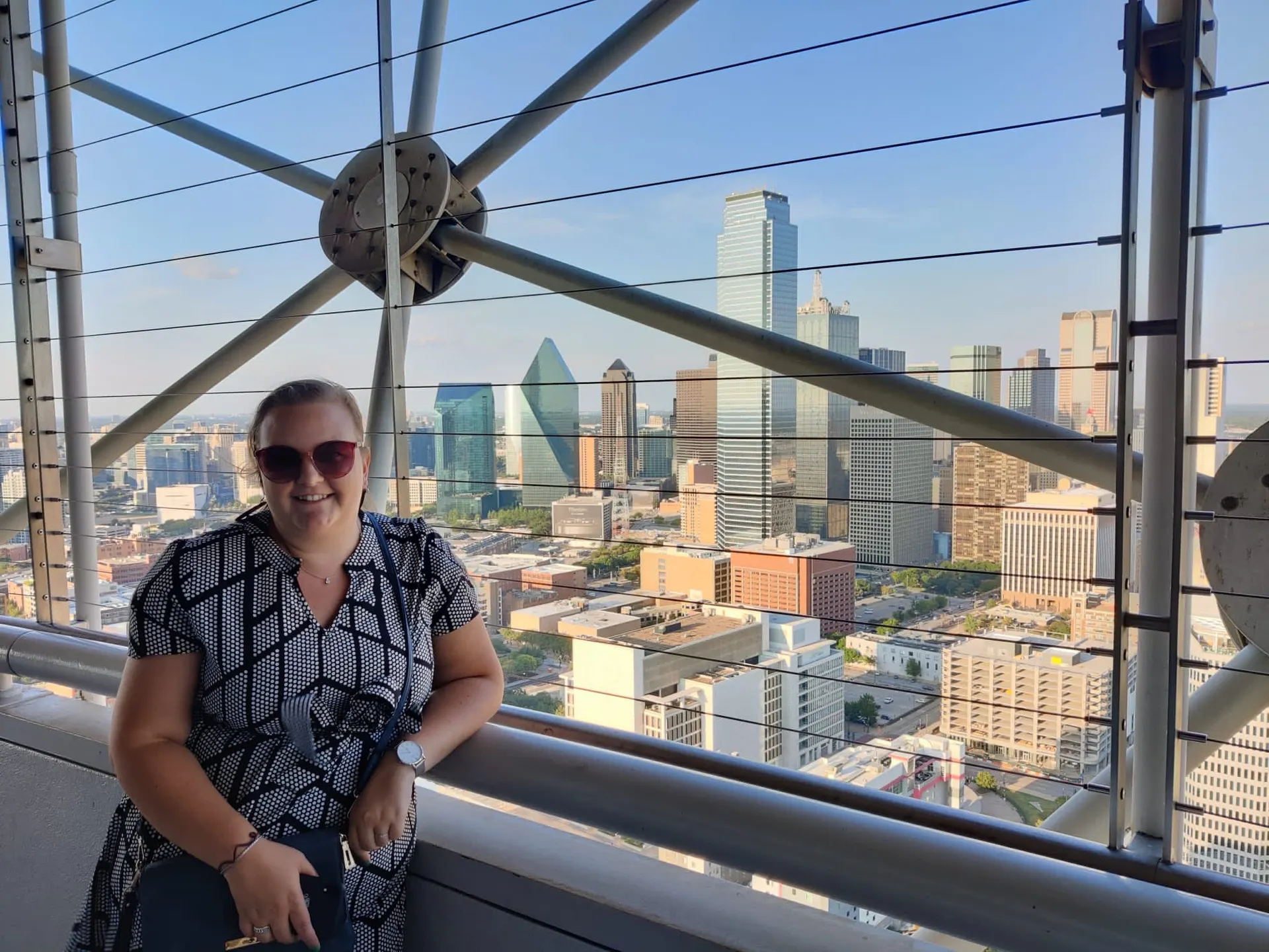 Leuke foto van een dame met een zonnebril in de linkerkant van de foto, je ziet een uitzicht van Dallas, Texas Amerika.