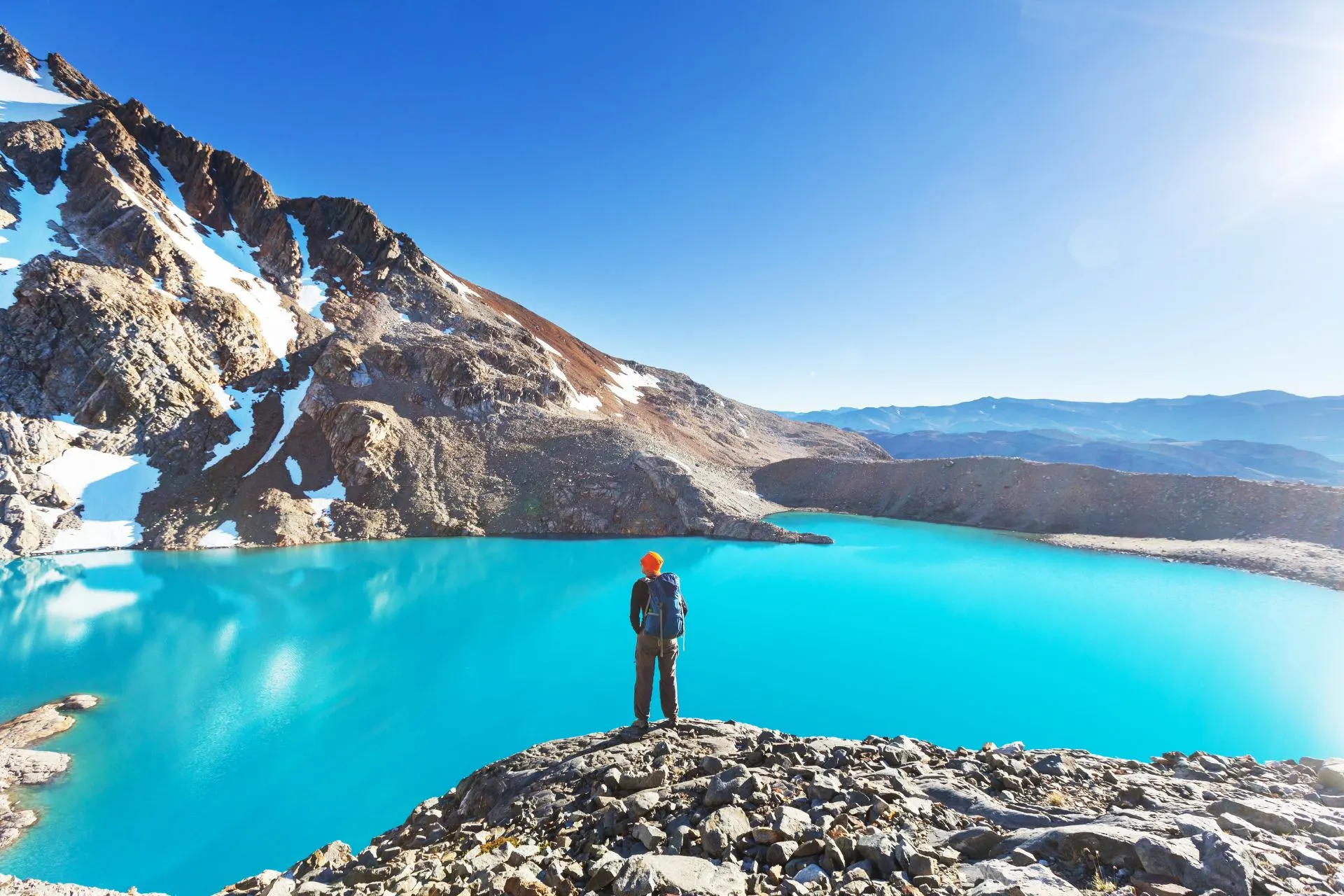 Wandelaar bij een helderblauw bergmeer in de Andes met indrukwekkend berglandschap tijdens een rondreis door Chili en Argentinië.
