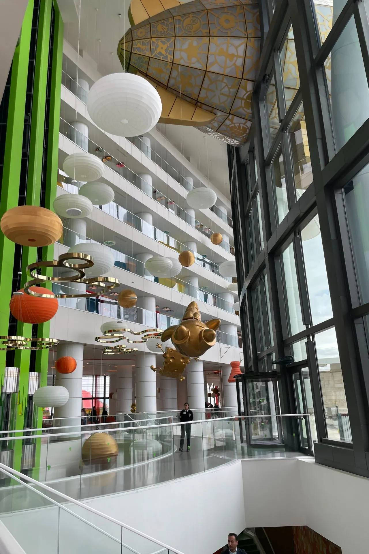 Binnenruimte van het hotel met groene accenten, grote open ruimte en decoratieve elementen zoals lampen en speelse vormen.