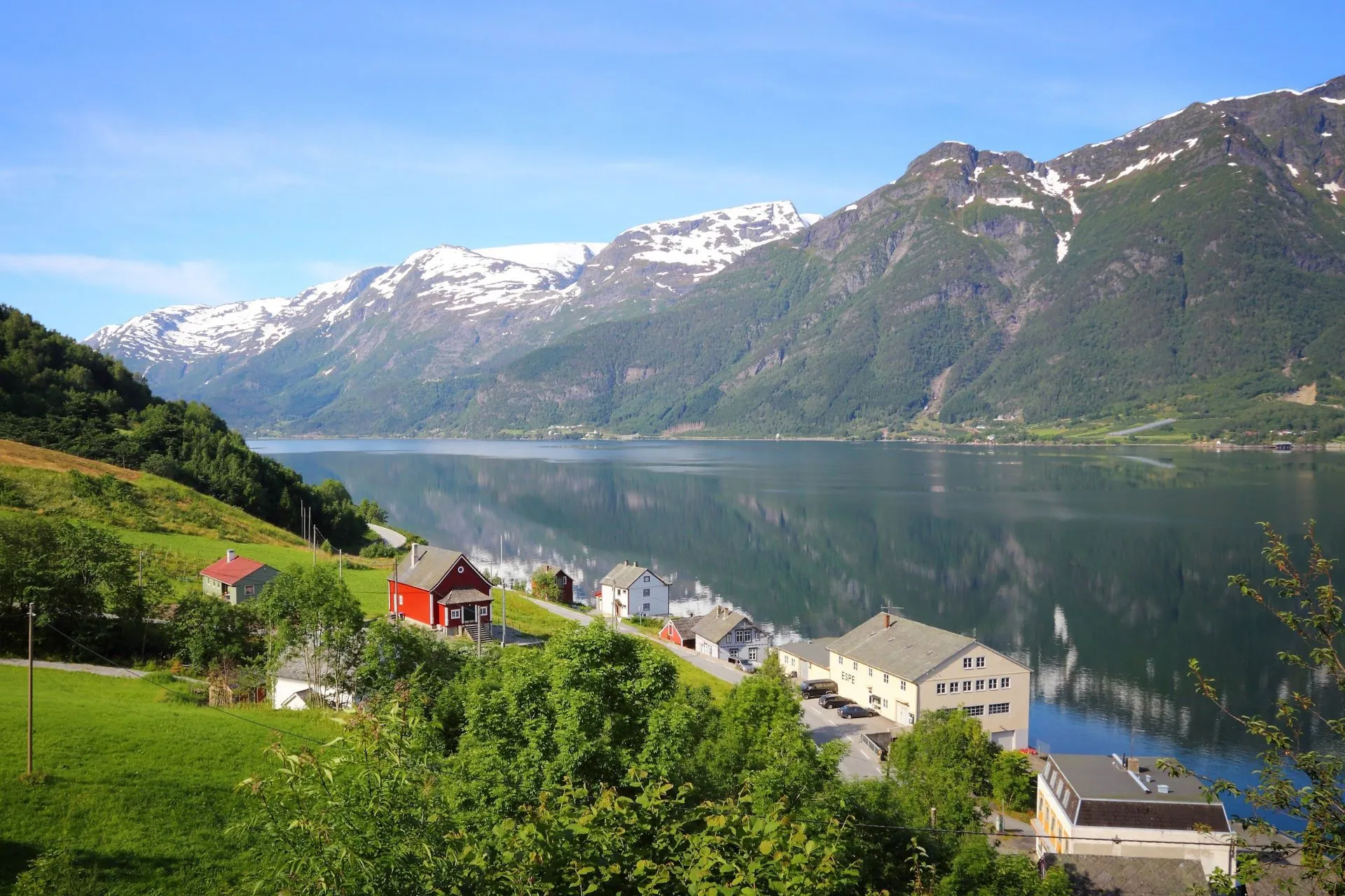 Rustiek fjordlandschap in Noorwegen met charmante huisjes aan het water, omlijst door imposante bergen en een kalm wateroppervlak