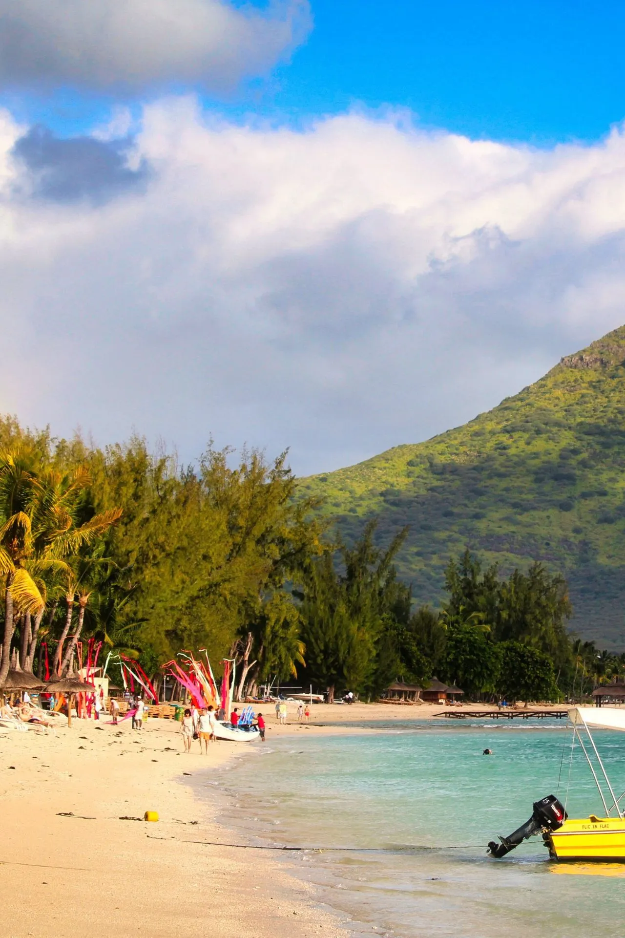 Een levendig strand op Mauritius met kleurrijke vlaggen, palmbomen en een helderblauwe zee. Perfect voor een all-inclusive vakantie op Mauritius met zon, zee en ontspanning.