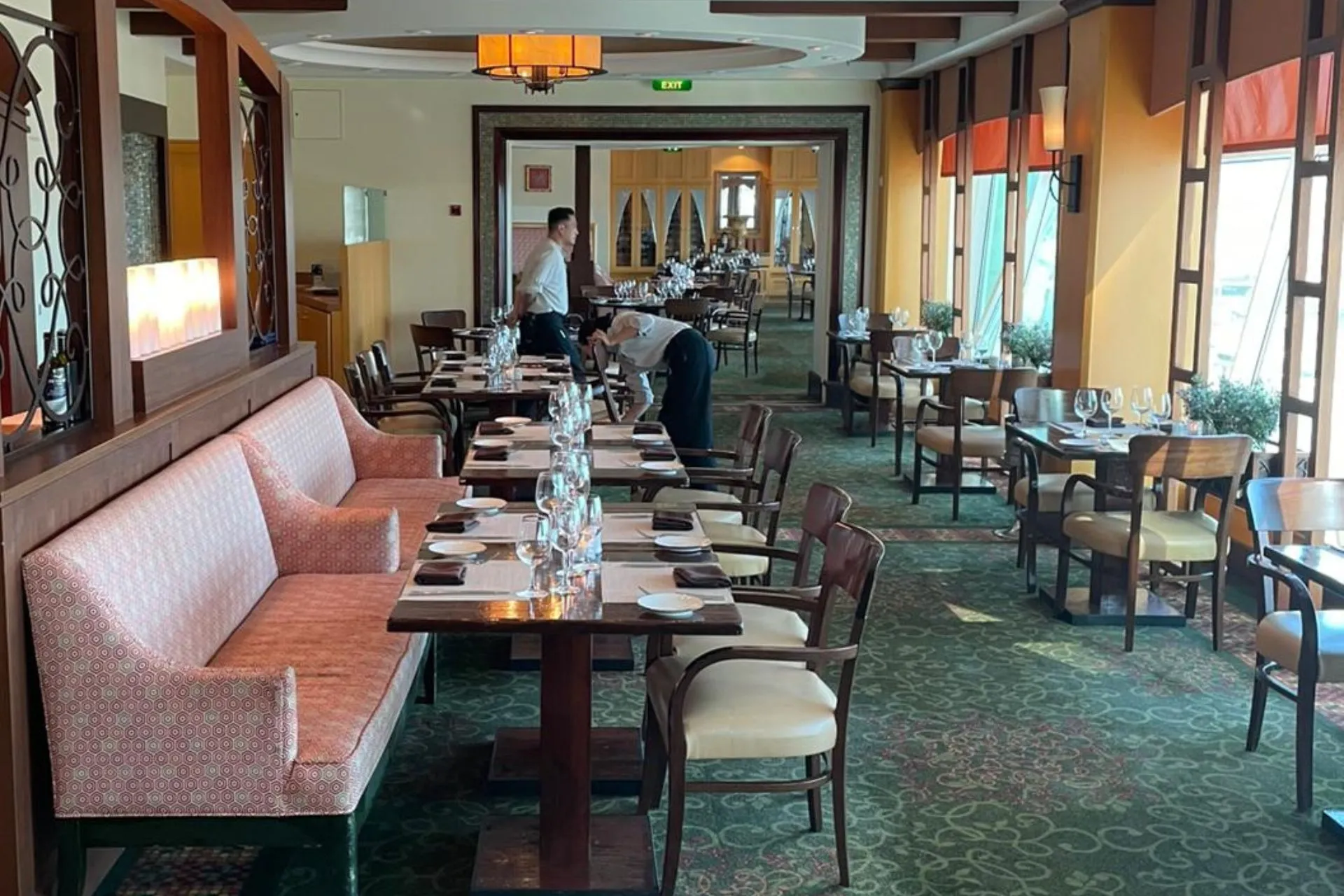 Intiem restaurant op de Independence of the Seas met gedekte tafels, houten meubilair en grote ramen die zorgen voor veel natuurlijk licht.