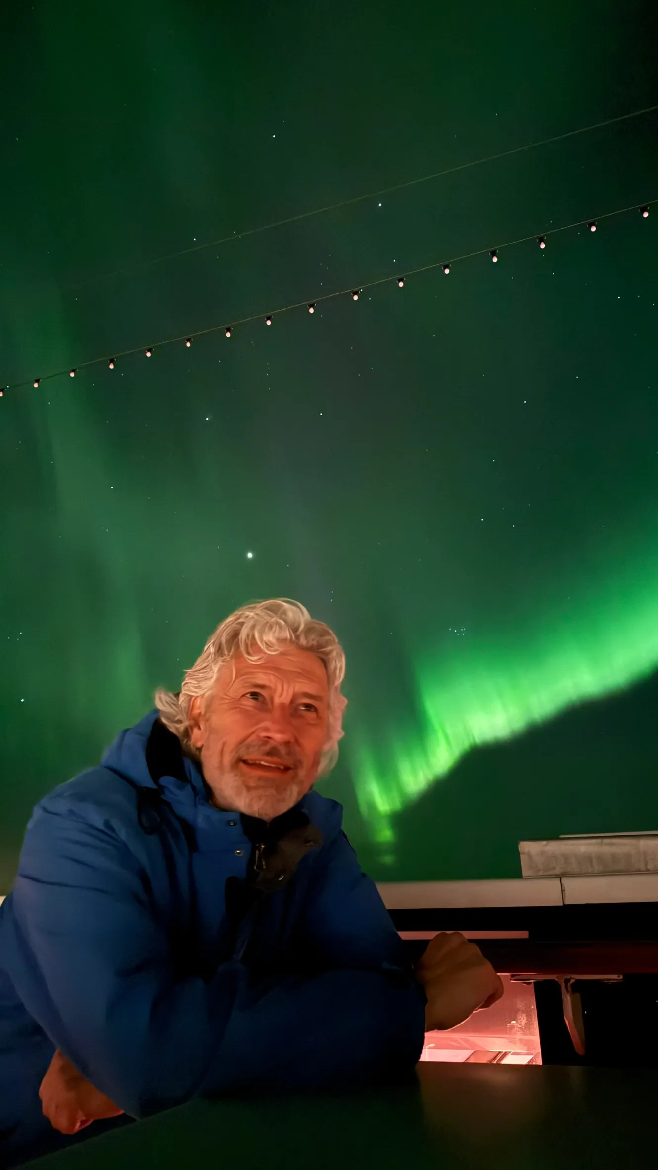 Man op de foto met groen noorderlicht in Zweden. Ad de Wit tijdens een Hapag Lloyd cruise